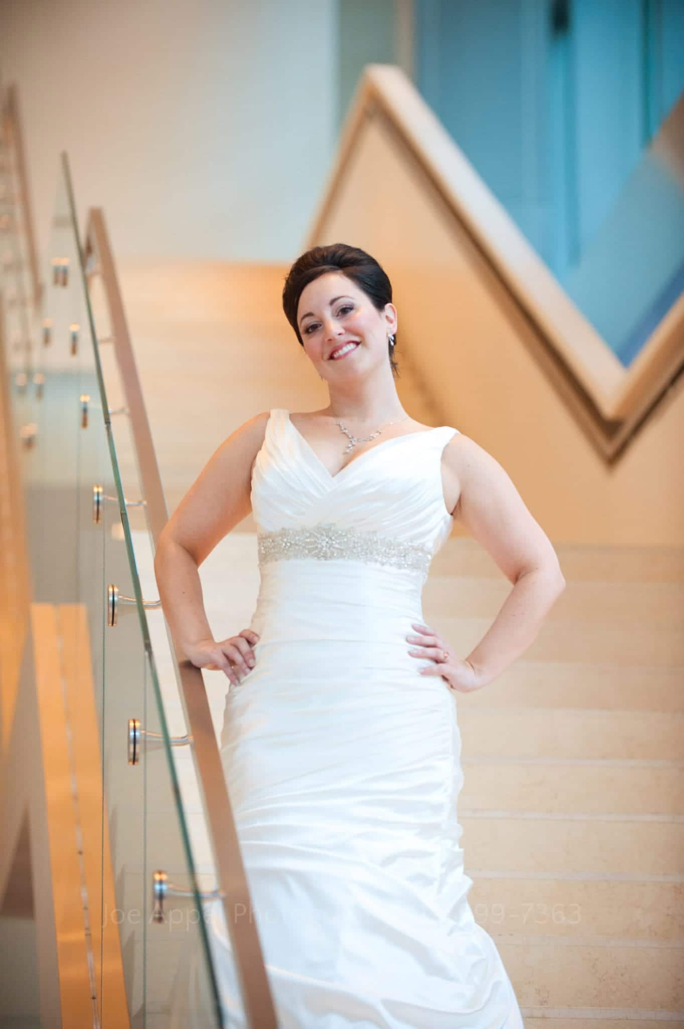 A bride stands with arms akimbo on a white stone staircase Fairmont Hotel Pittsburgh Weddings