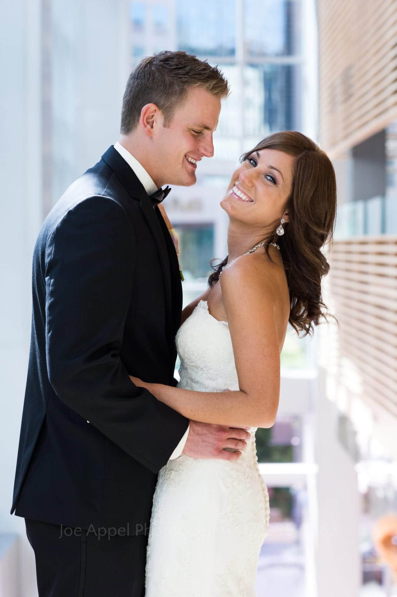 A bride looks at the camera as she stands with her groom. He's looking at her Fairmont Hotel Pittsburgh Weddings.