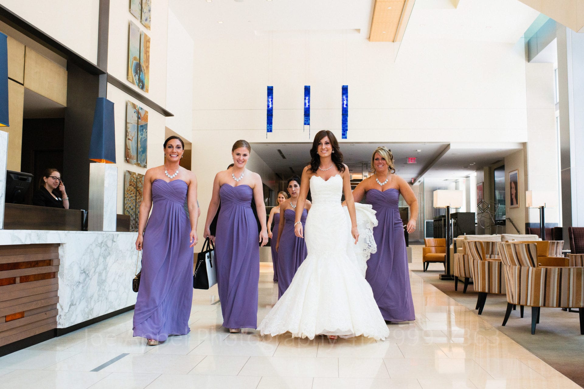 A bride and her purple-dressed bridesmaids walk through the lobby of the Fairmont Hotel in Pittsburgh Fairmont Hotel Pittsburgh Weddings