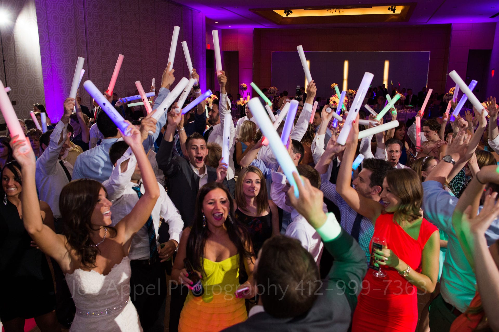 Fairmont Hotel Pittsburgh Weddings A crowded dance floor filled with guests who are waving lighted foam tubes in the air.
