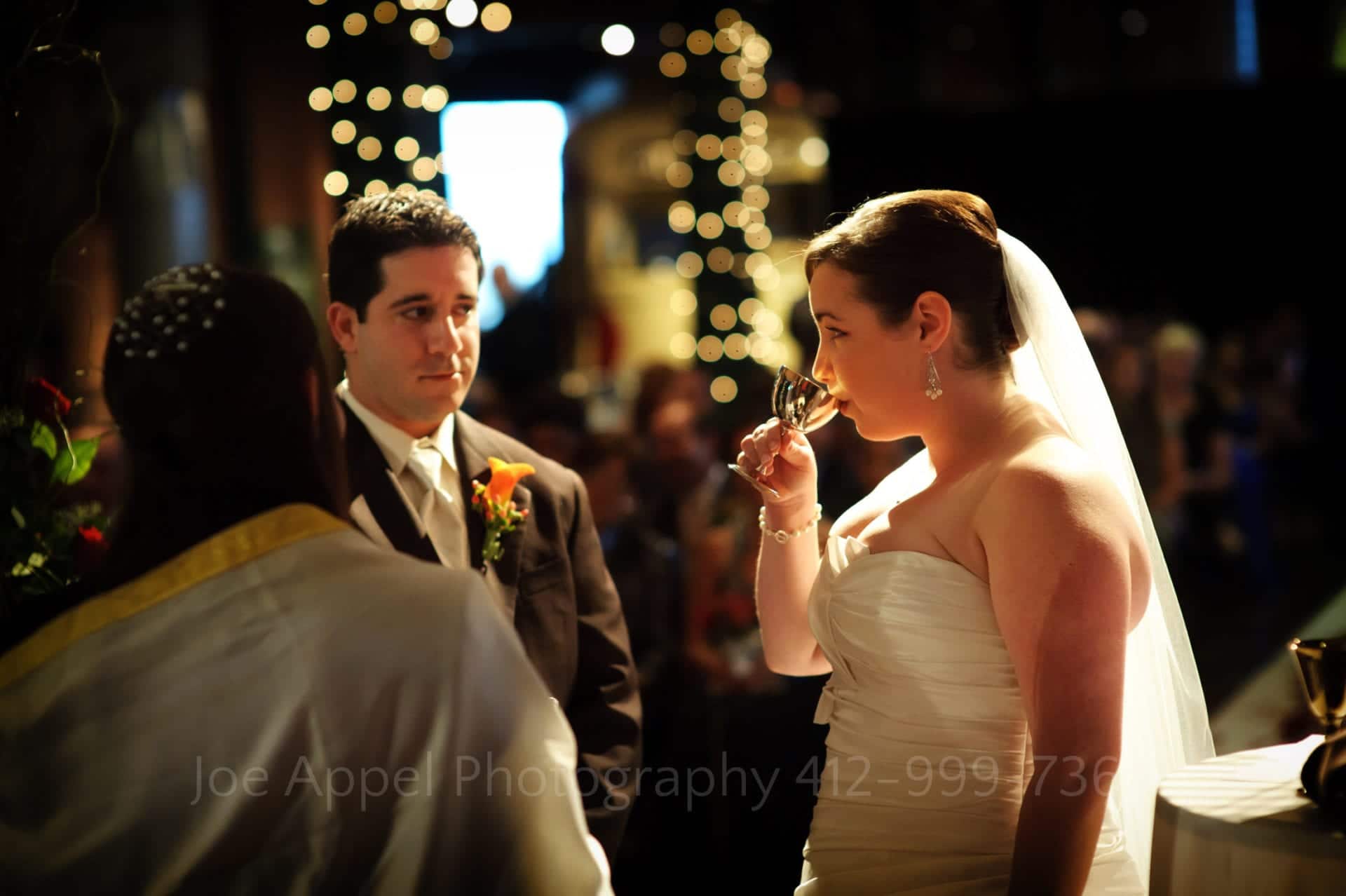 Bride drinks from a kiddush cup during her wedding ceremony in the Great Hall at the Heinz History Center