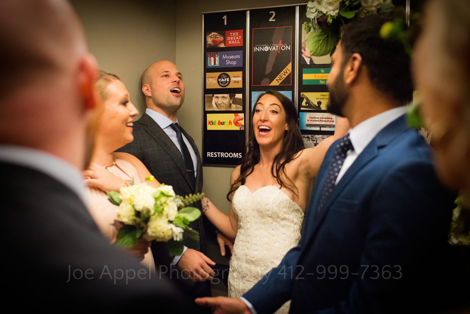 Bride and groom laugh as they stand with their bridal party in the elevator at the Heinz History Center.