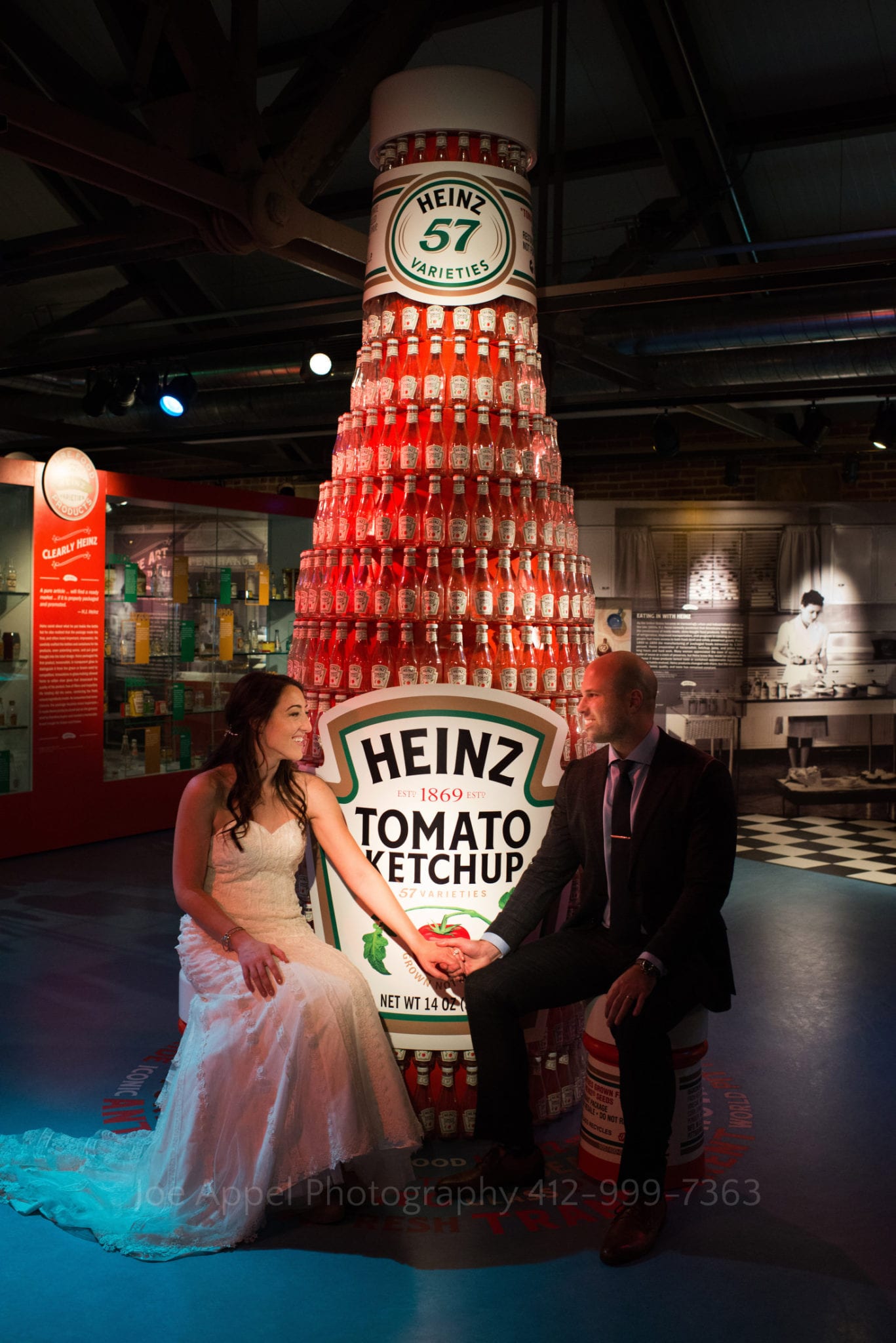 Couple sits by a giant display of a ketchup bottle at the Heinz History Center