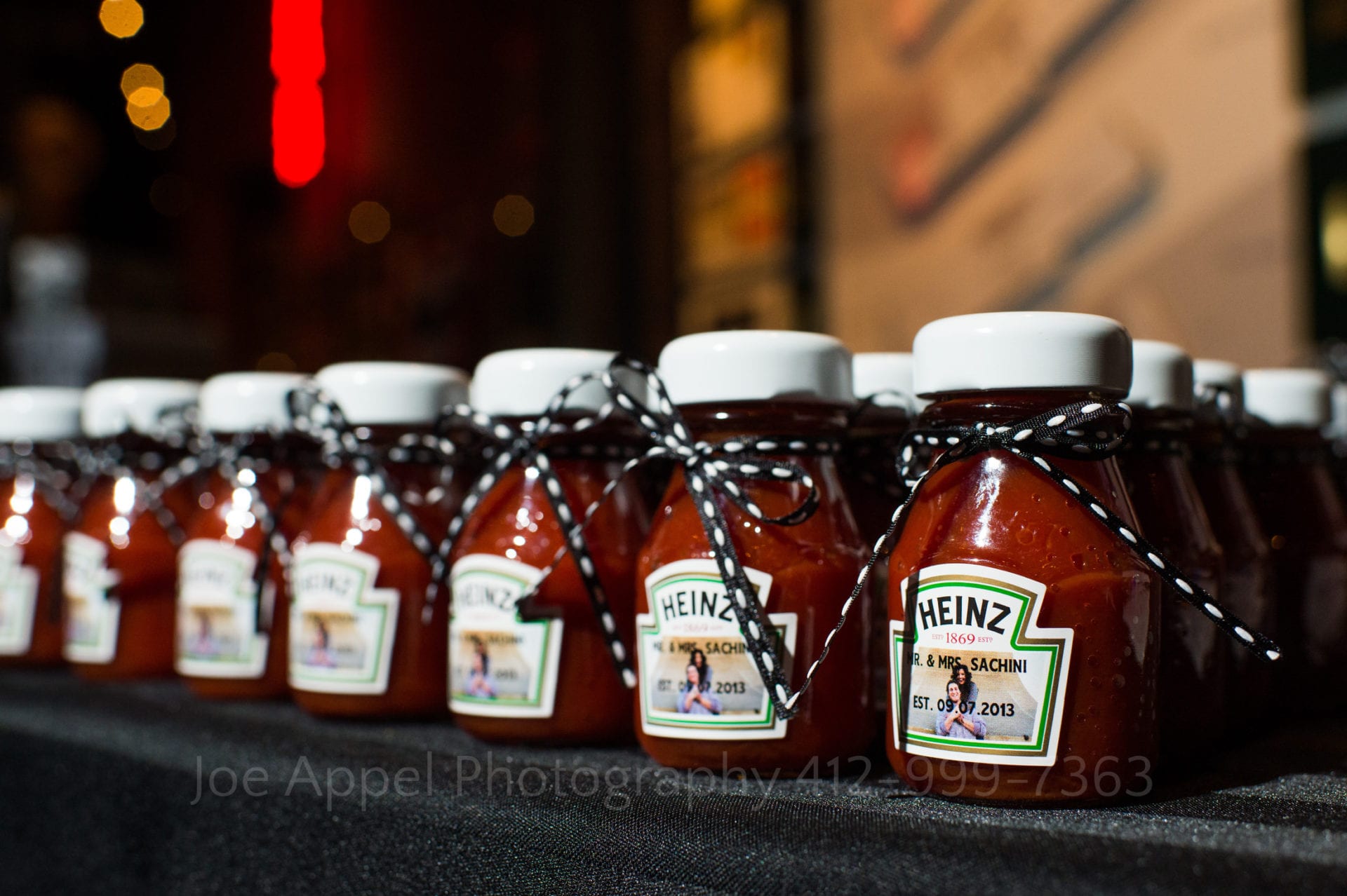 small ketchup bottles with personalized labels are favors for guests at a wedding.