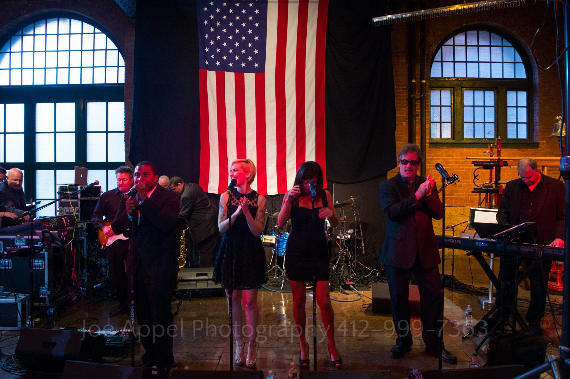 A band plays in front of a large American flag and arched windows at the Heinz History Center.