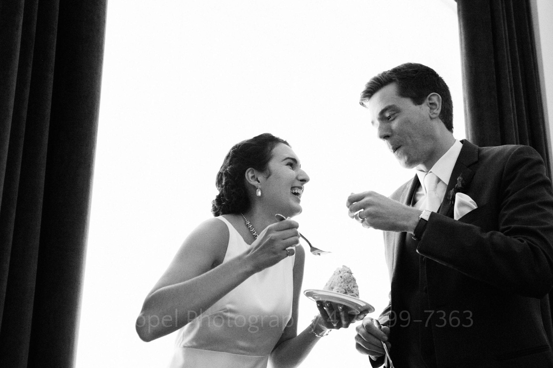 a bride and groom share a piece of wedding cake