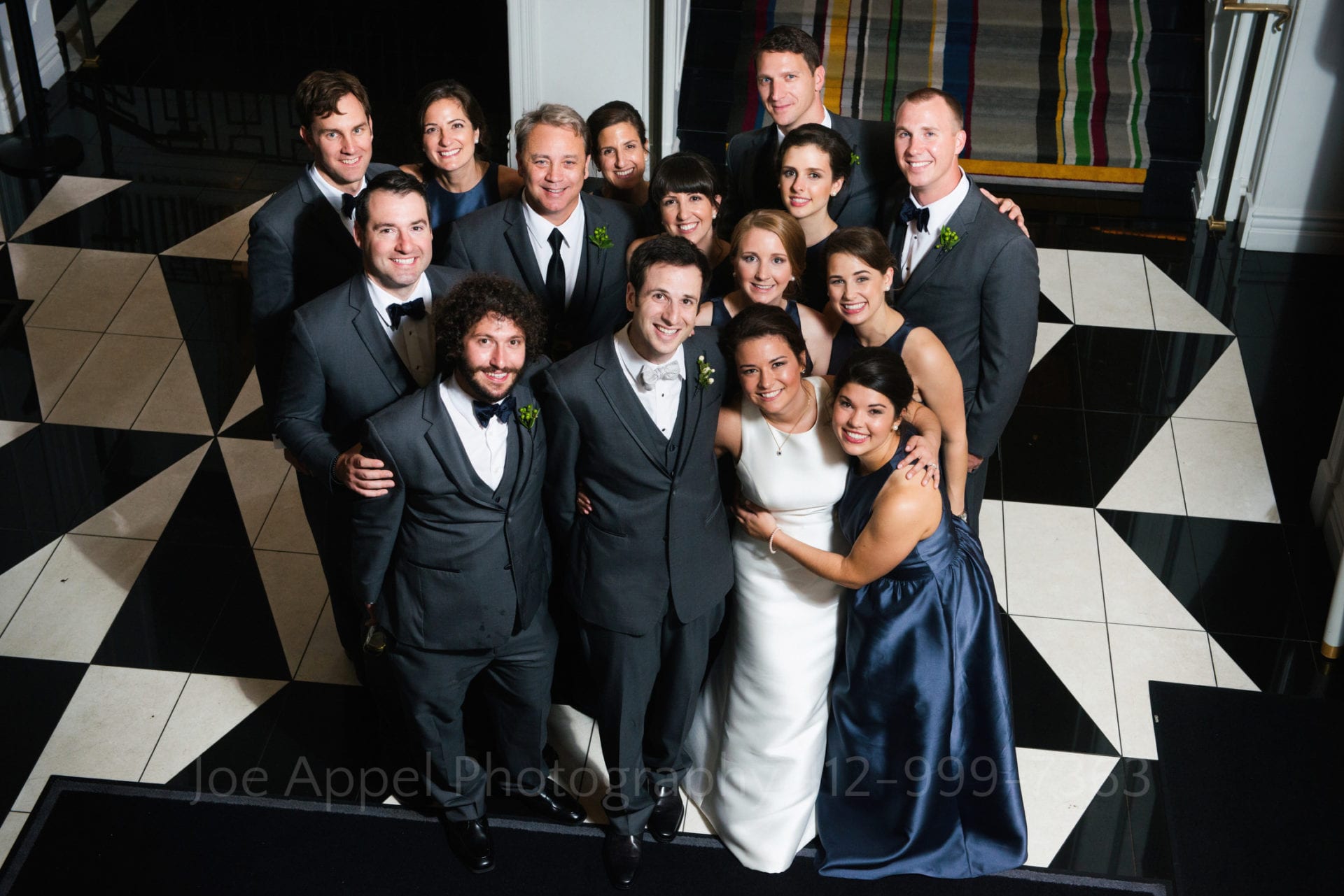 a bride and groom gather together with their wedding party on a black and white checkered floor