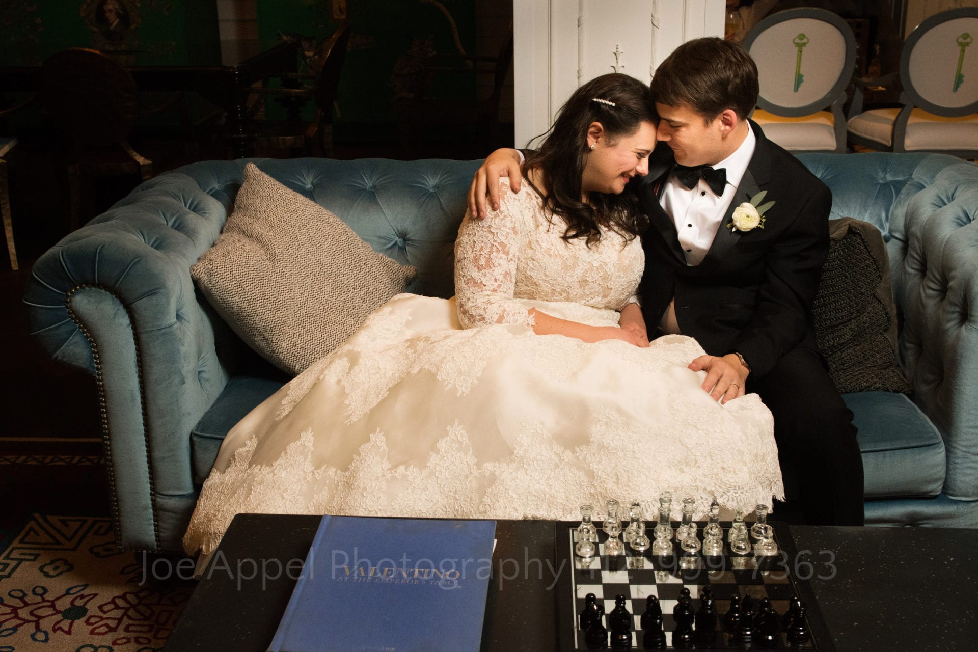 a groom embraces his bride on a blue couch