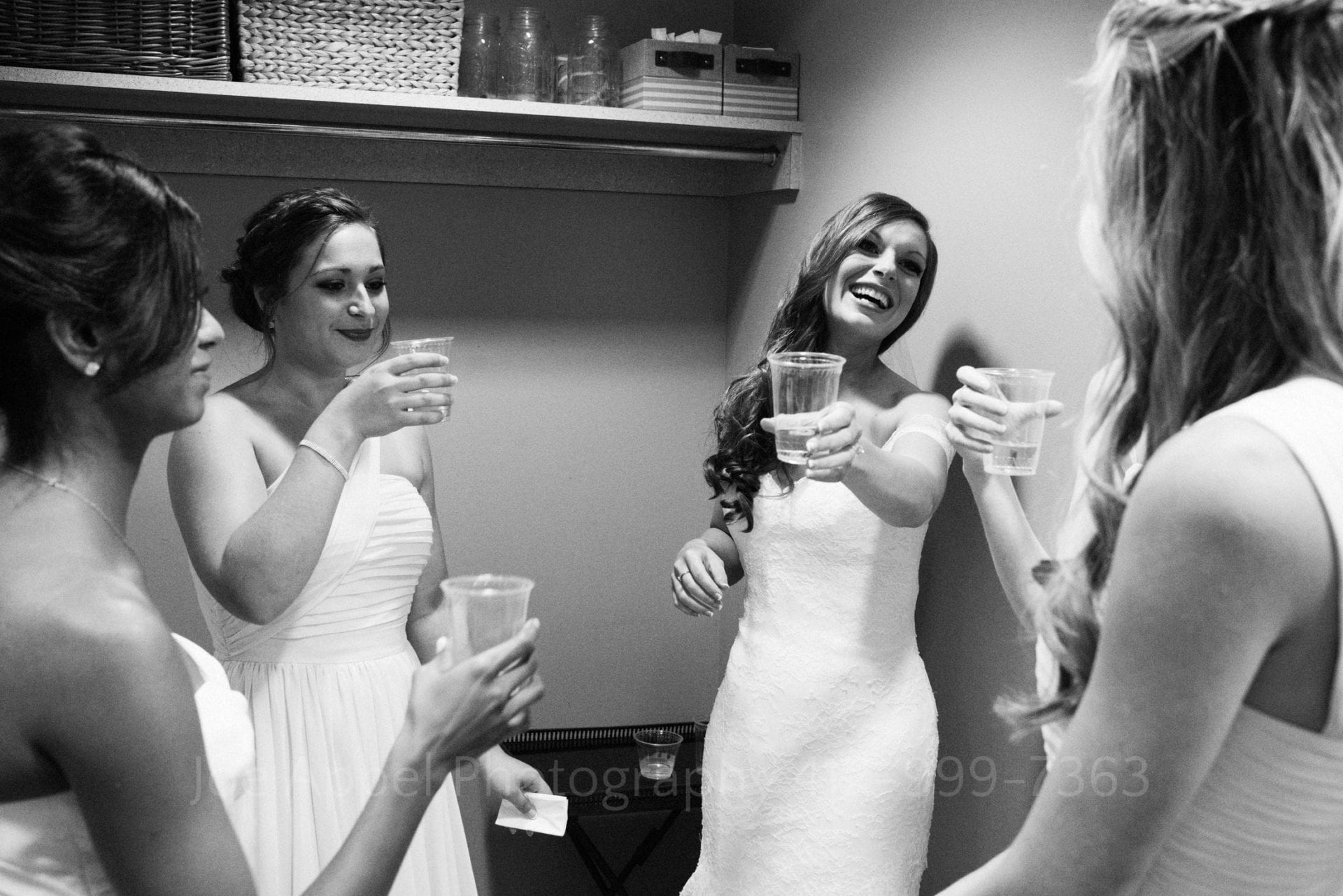 a bride and her bridesmaids laugh and make a toast with plastic cups Phipps Conservatory Weddings