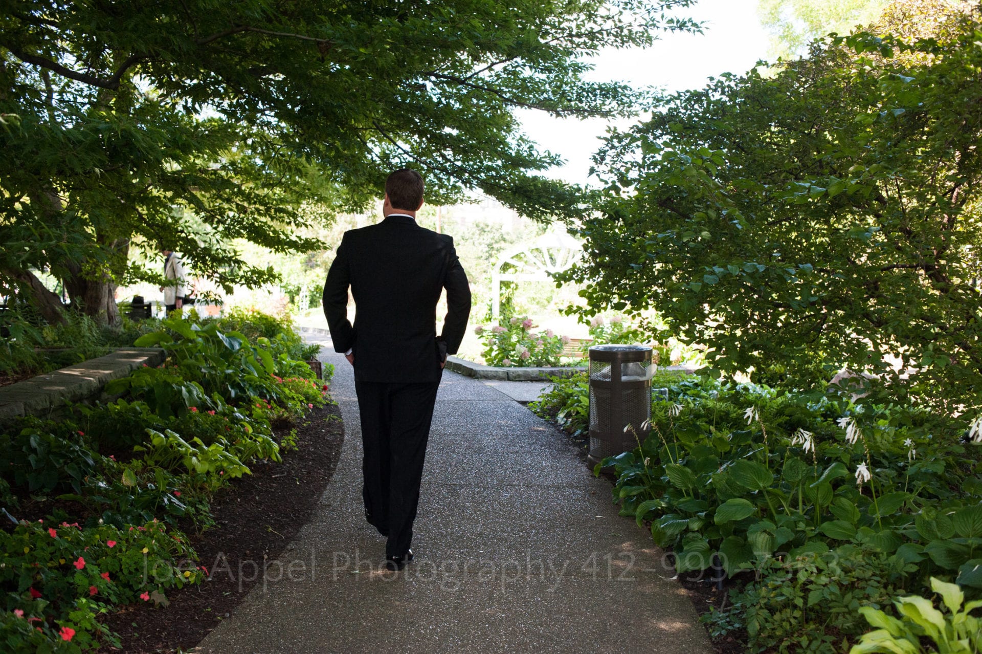 a groom walks on a path through a green garden Phipps Conservatory Weddings