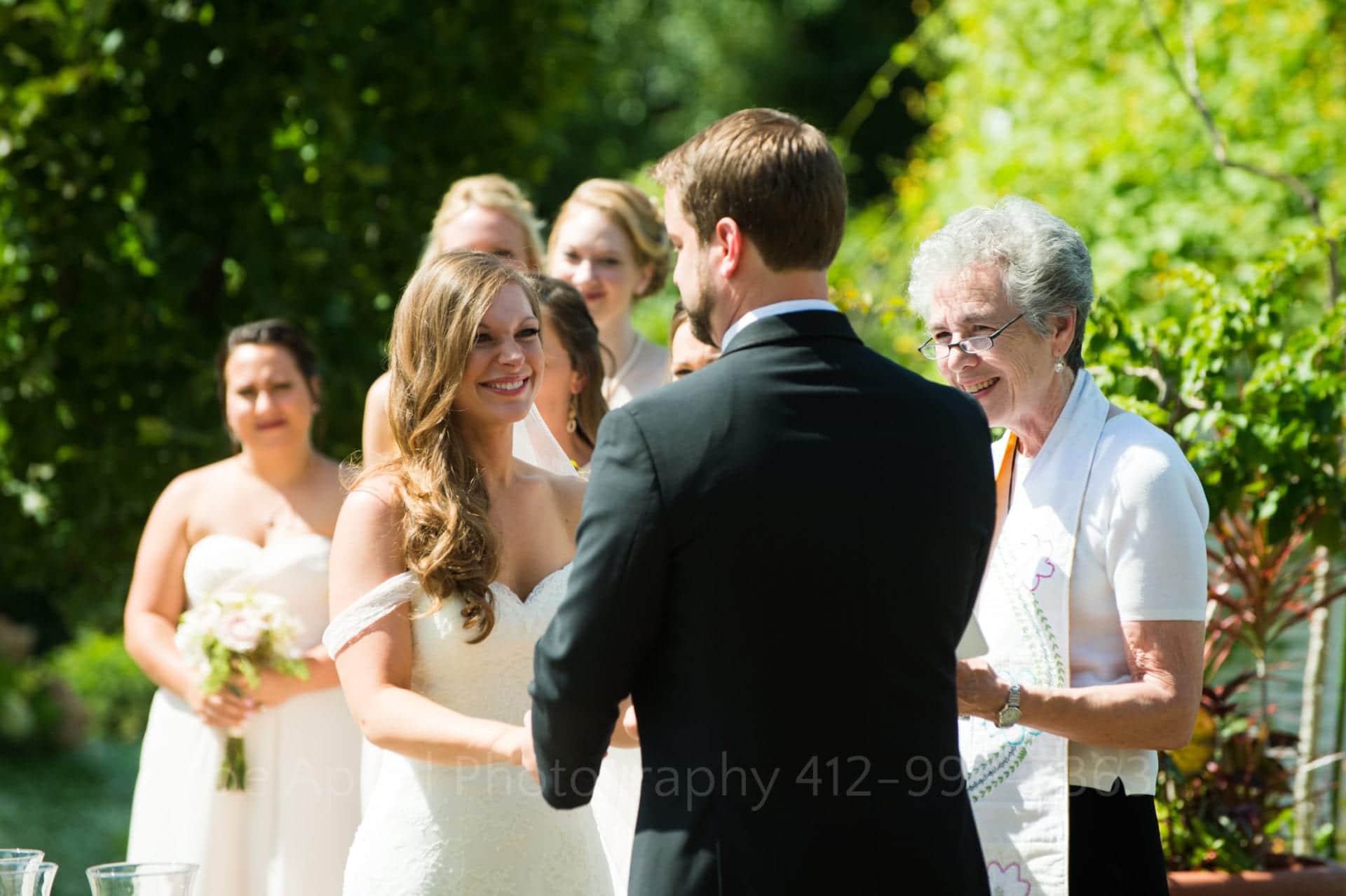 a bride smiles at her groom as they say their vows in a garden Phipps Conservatory Weddings
