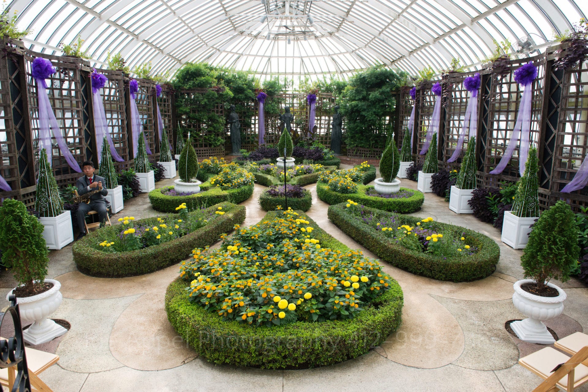 a garden with shrubbery and yellow flowers decorated with purple Phipps Conservatory Weddings