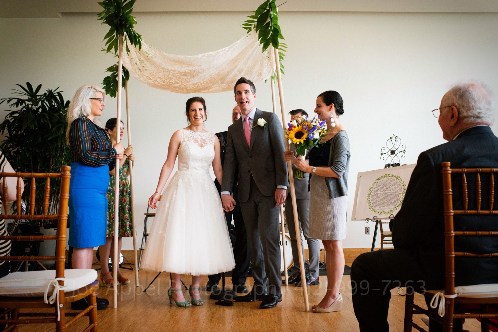 a bride and groom laugh while saying their vows beside a white curtain Phipps Conservatory Weddings