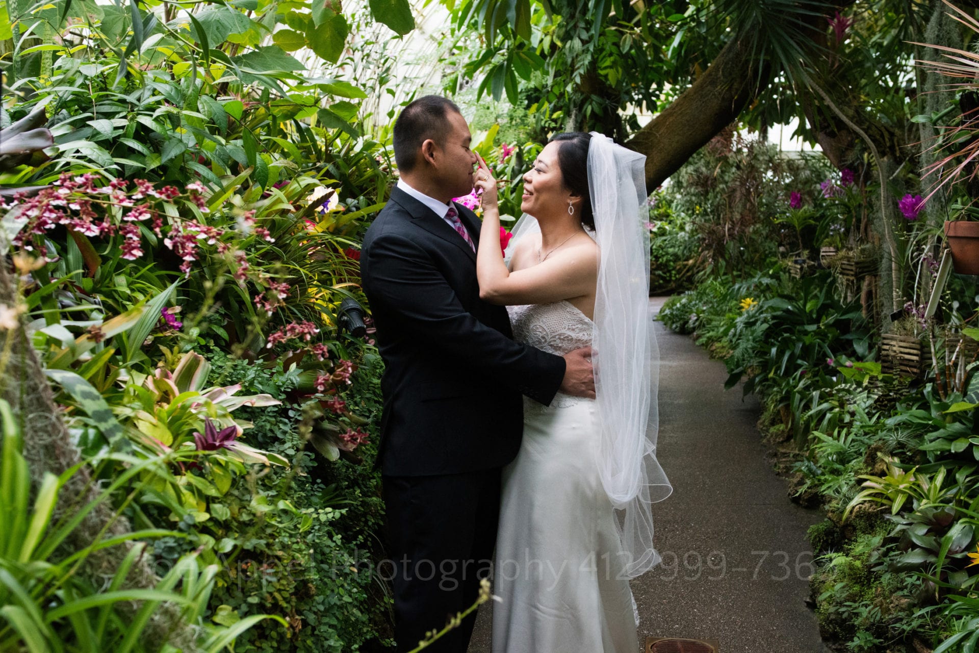 a bride touches her grooms nose as they stand in a tropical garden Phipps Conservatory Weddings