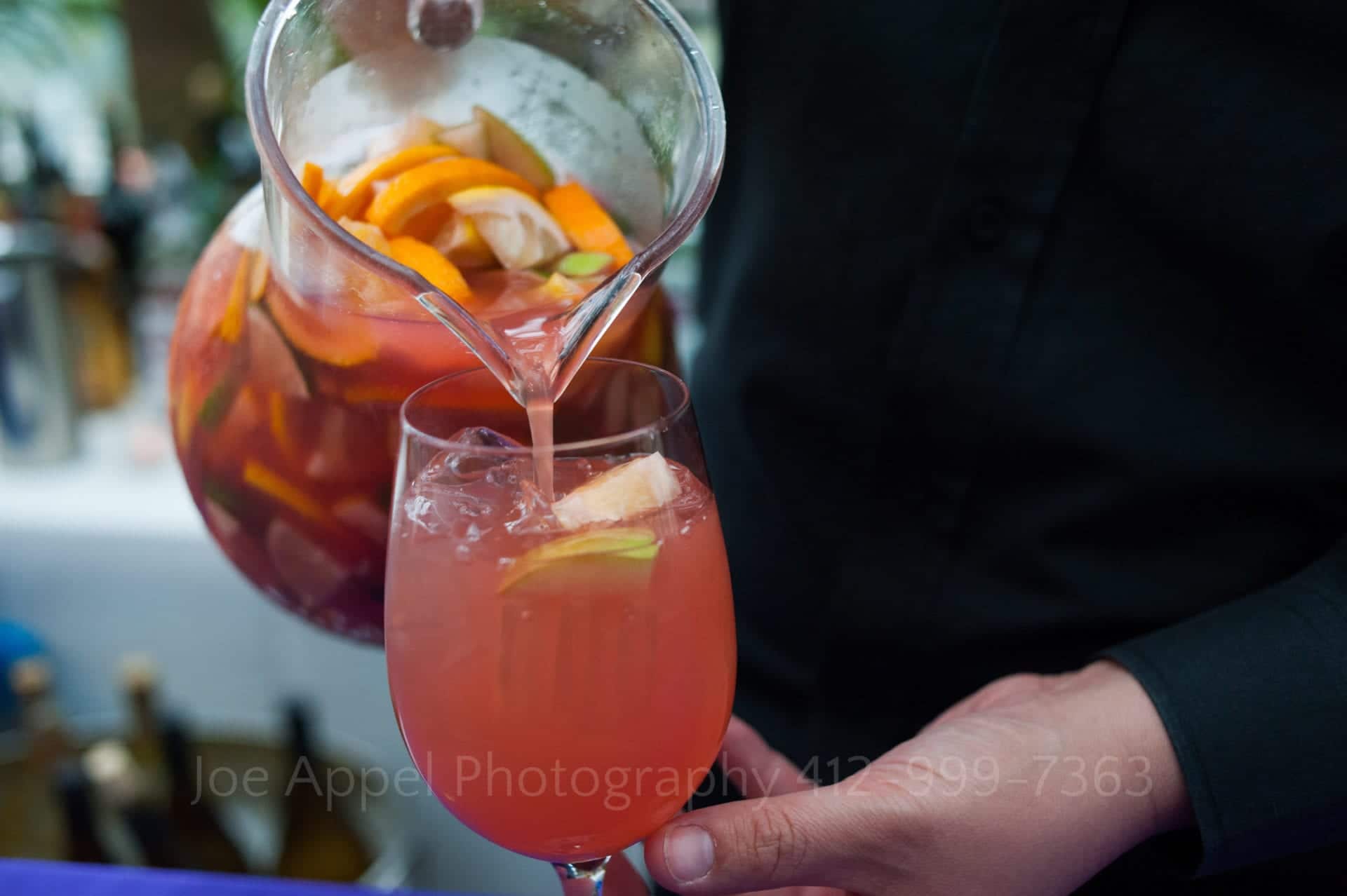 a server pours sangria with limes and oranges Phipps Conservatory Weddings