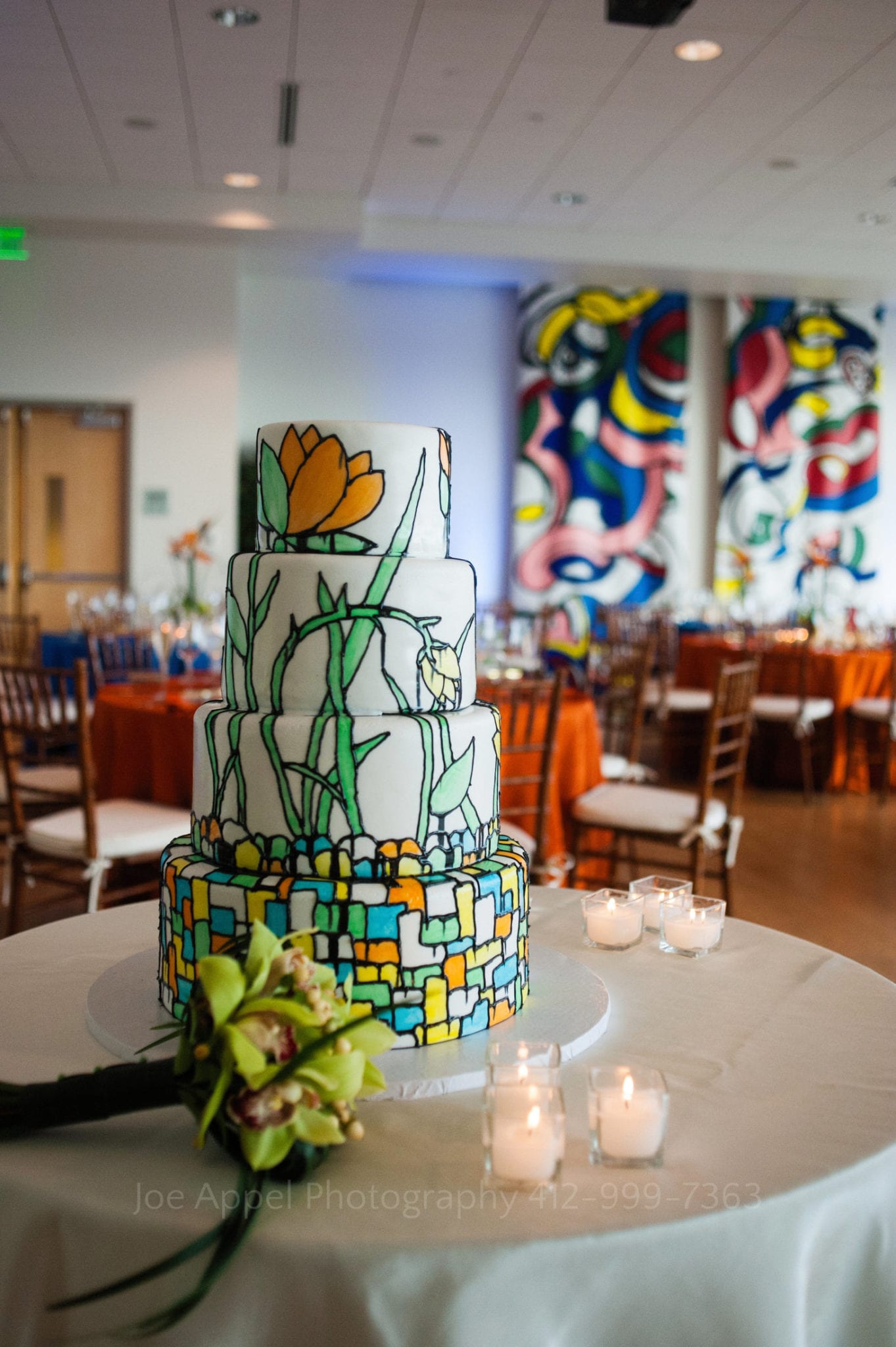 a wedding cake with a green blue orange and yellow floral design Phipps Conservatory Weddings