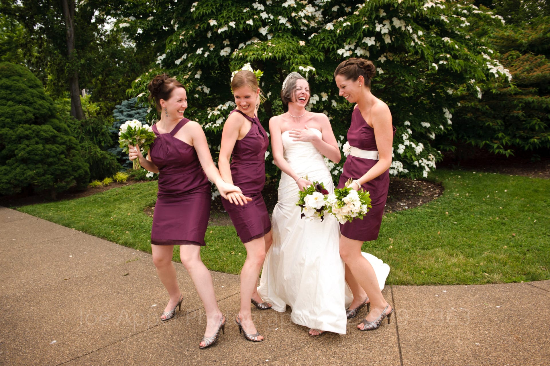 bridesmaids in purple dresses laugh and pose with the bride Phipps Conservatory Weddings