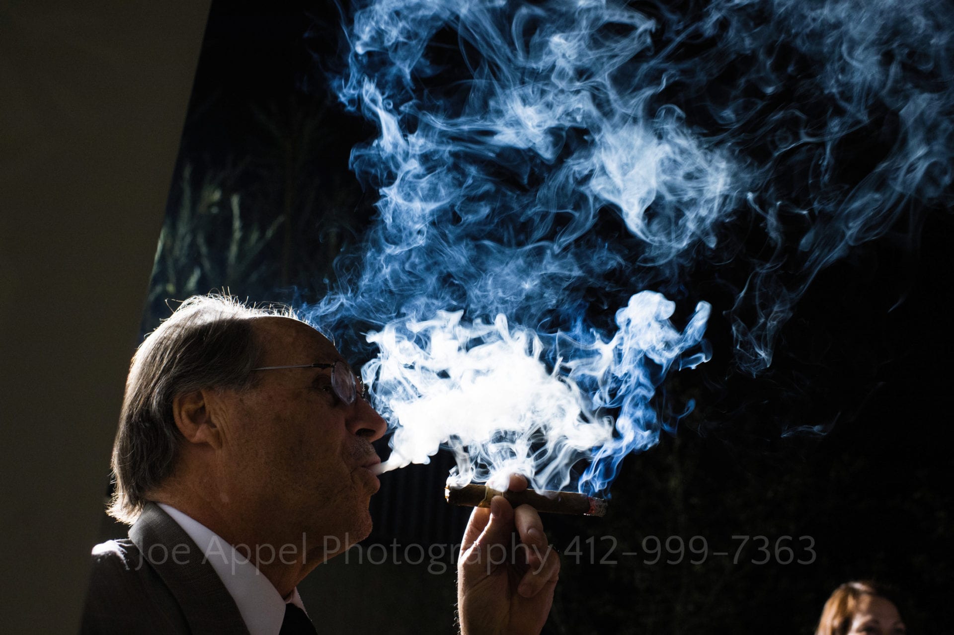a man blows smoke from a cigar into the night sky Phipps Conservatory Weddings