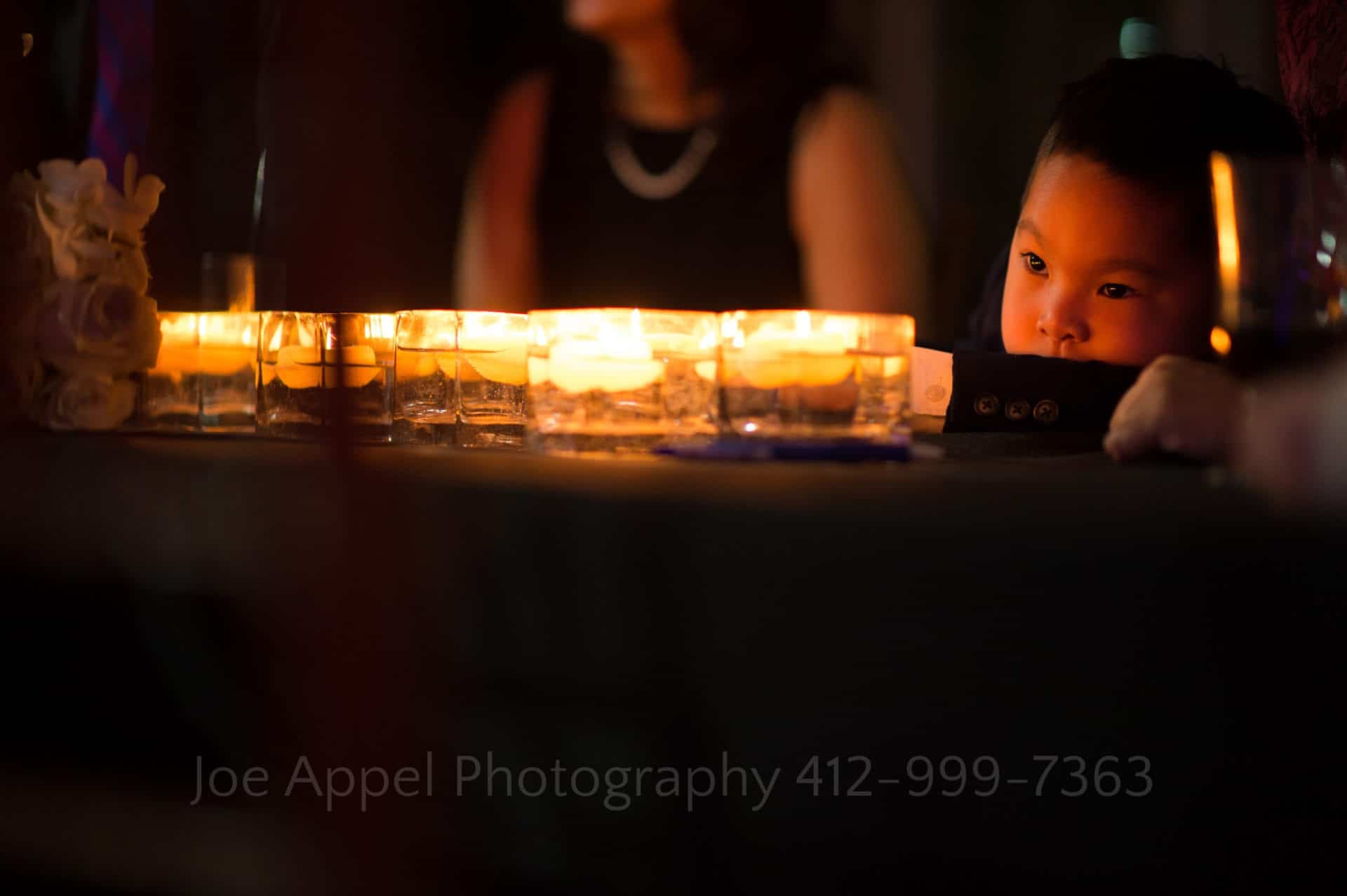a little boy looks at the illuminated candles Phipps Conservatory Weddings