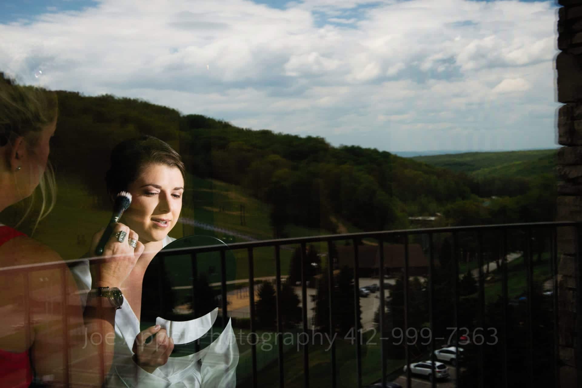 a bride looks at her reflection with green hills and a blue sky behind her Seven Springs Weddings