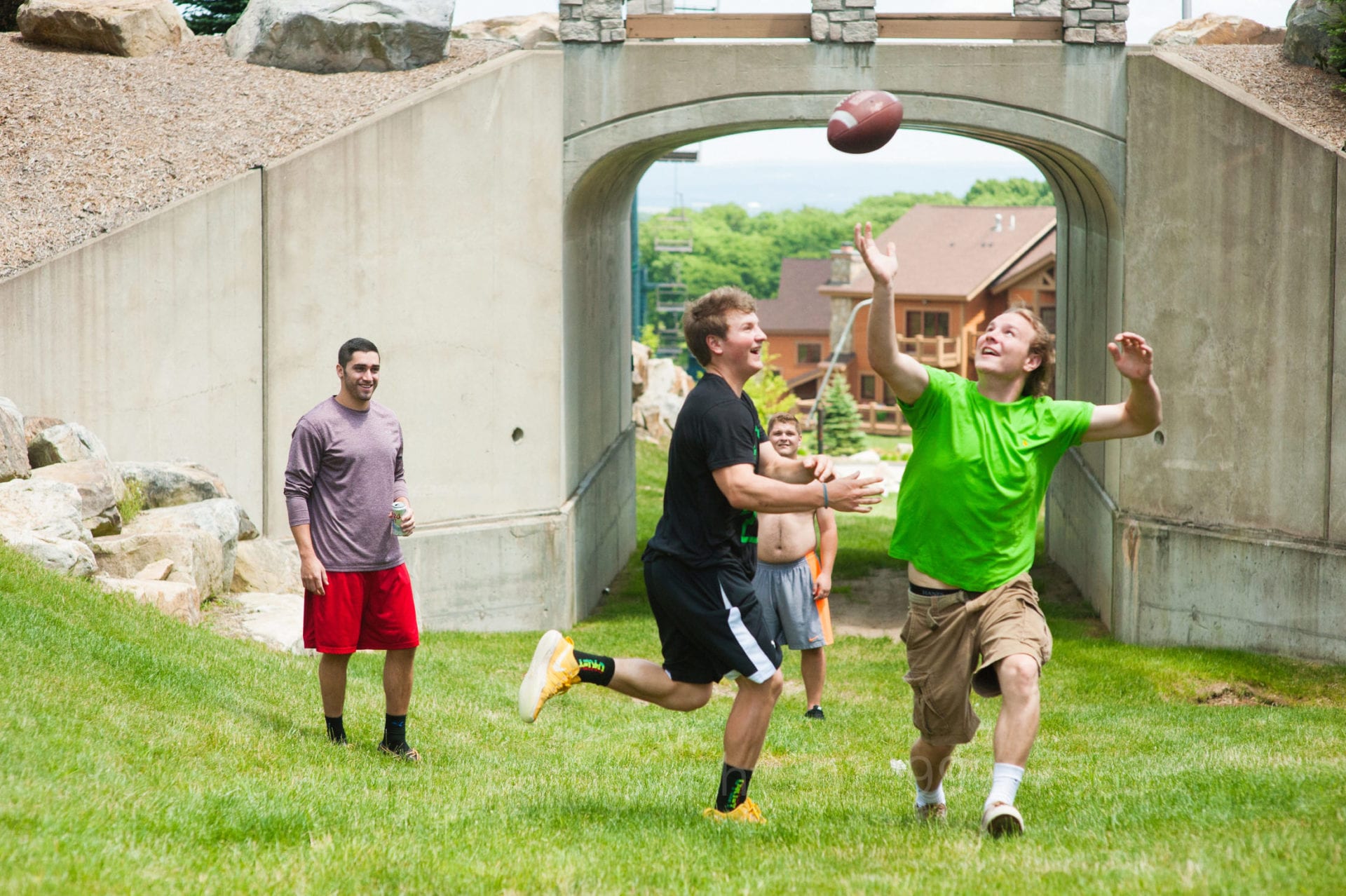 wedding guests play football in a grassy field Seven Springs Weddings