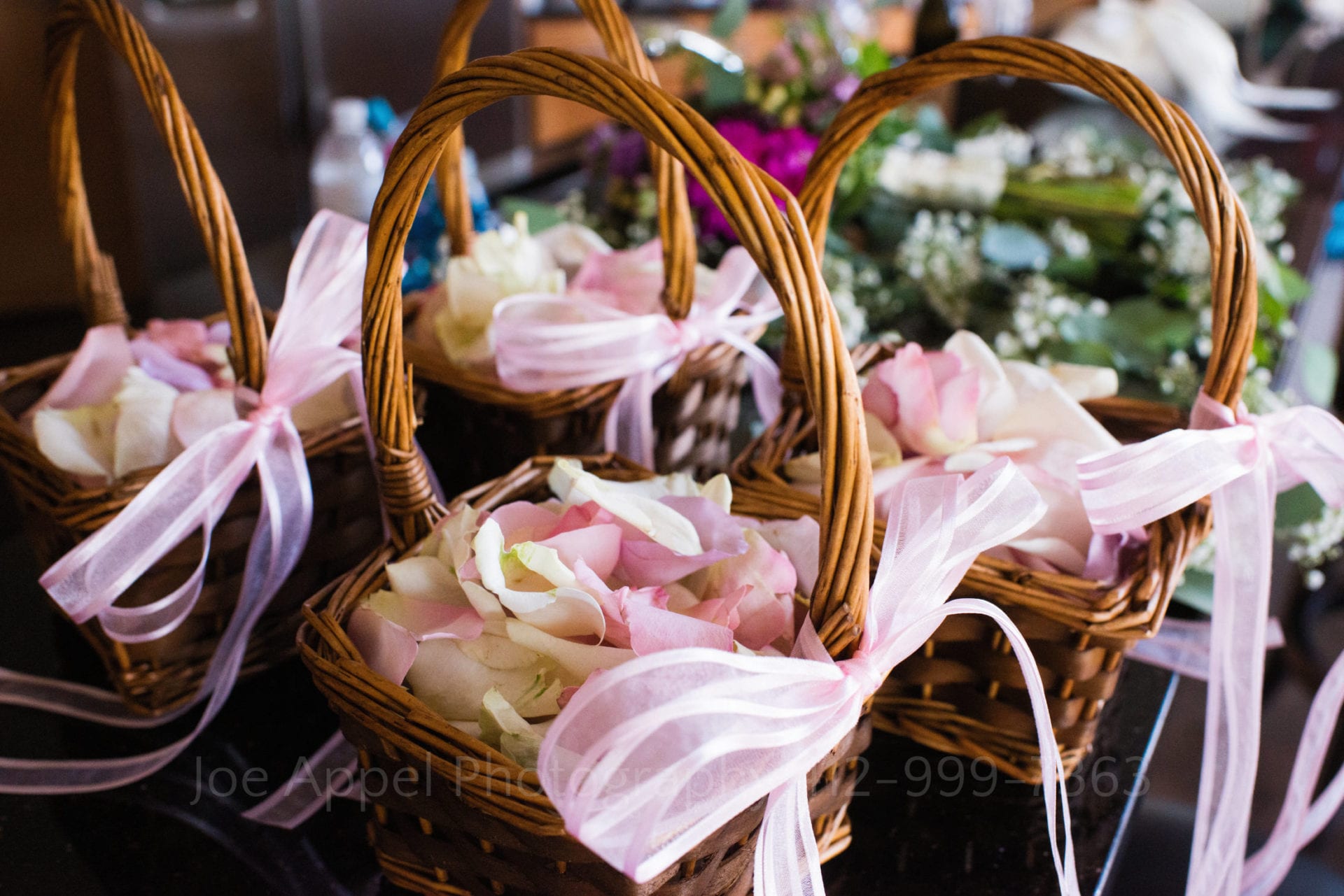 wicker baskets filled with pink flower petals and tied with pink ribbon Seven Springs Weddings