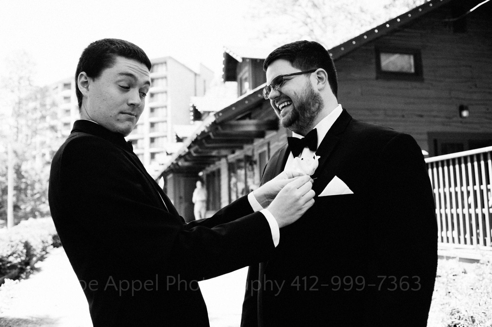 a groomsman pins a flower on another groomsman Seven Springs Weddings