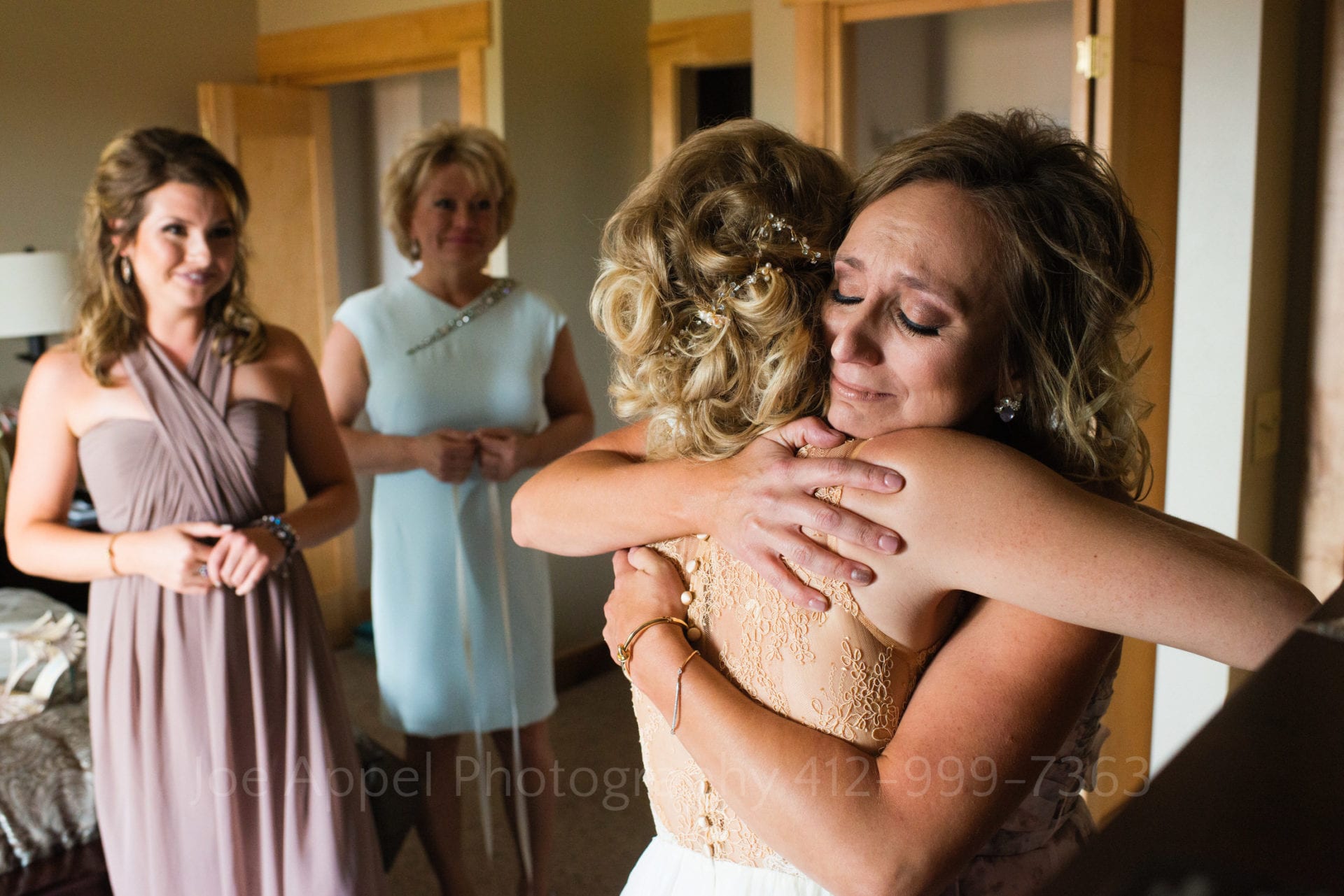 a woman hugs a bride as two other women smile and watch Seven Springs Weddings