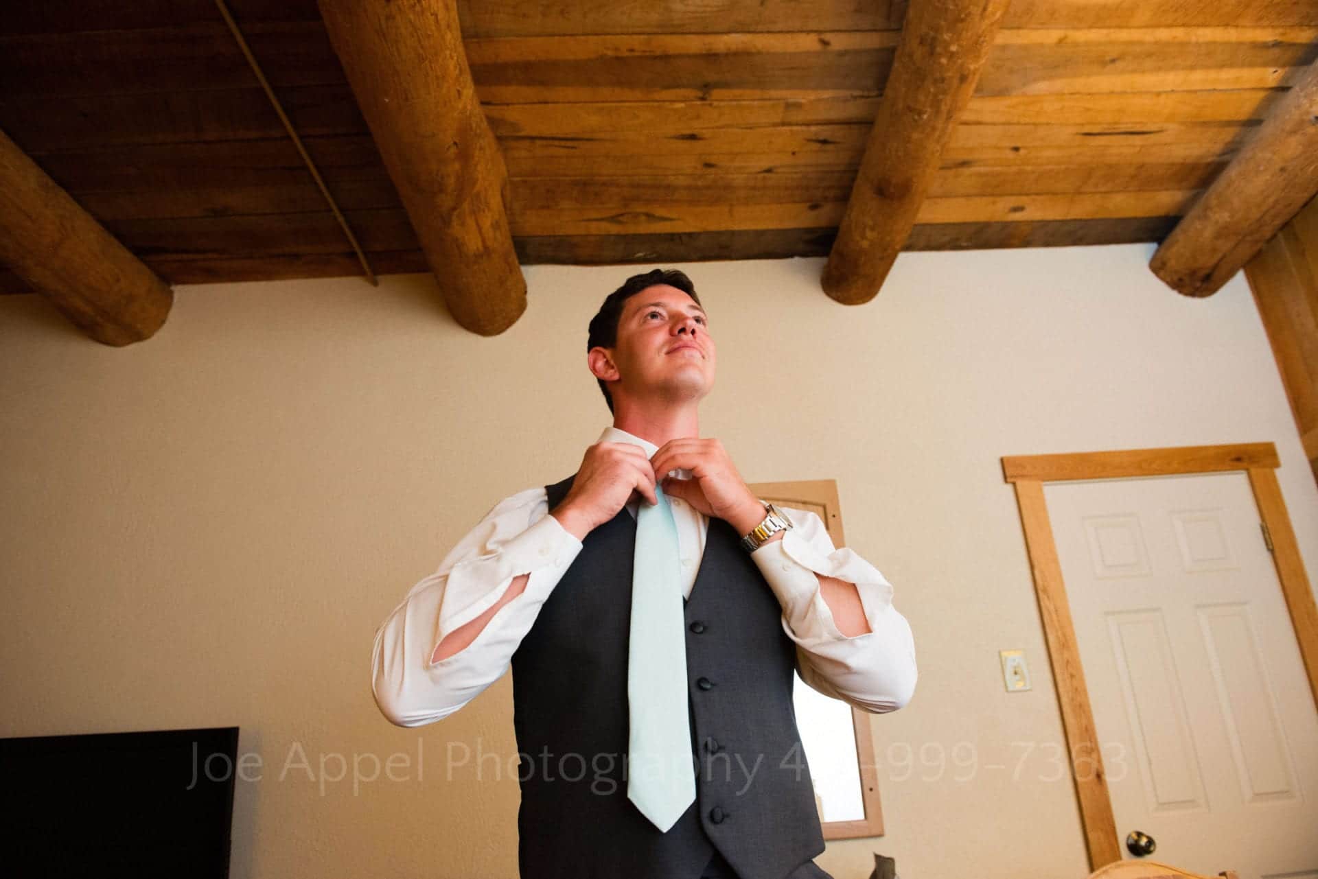 a groom ties his light blue neck tie Seven Springs Weddings
