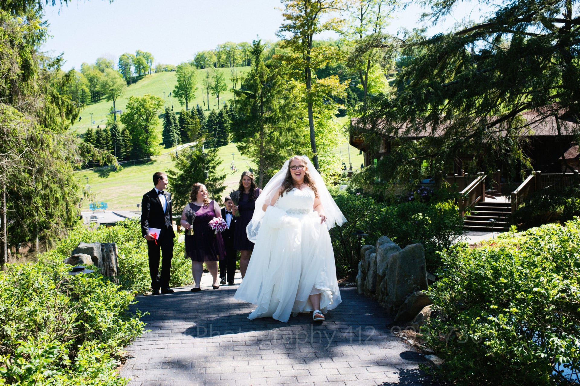 a bride walks on a path surrounded by grassy green hills Seven Springs Weddings