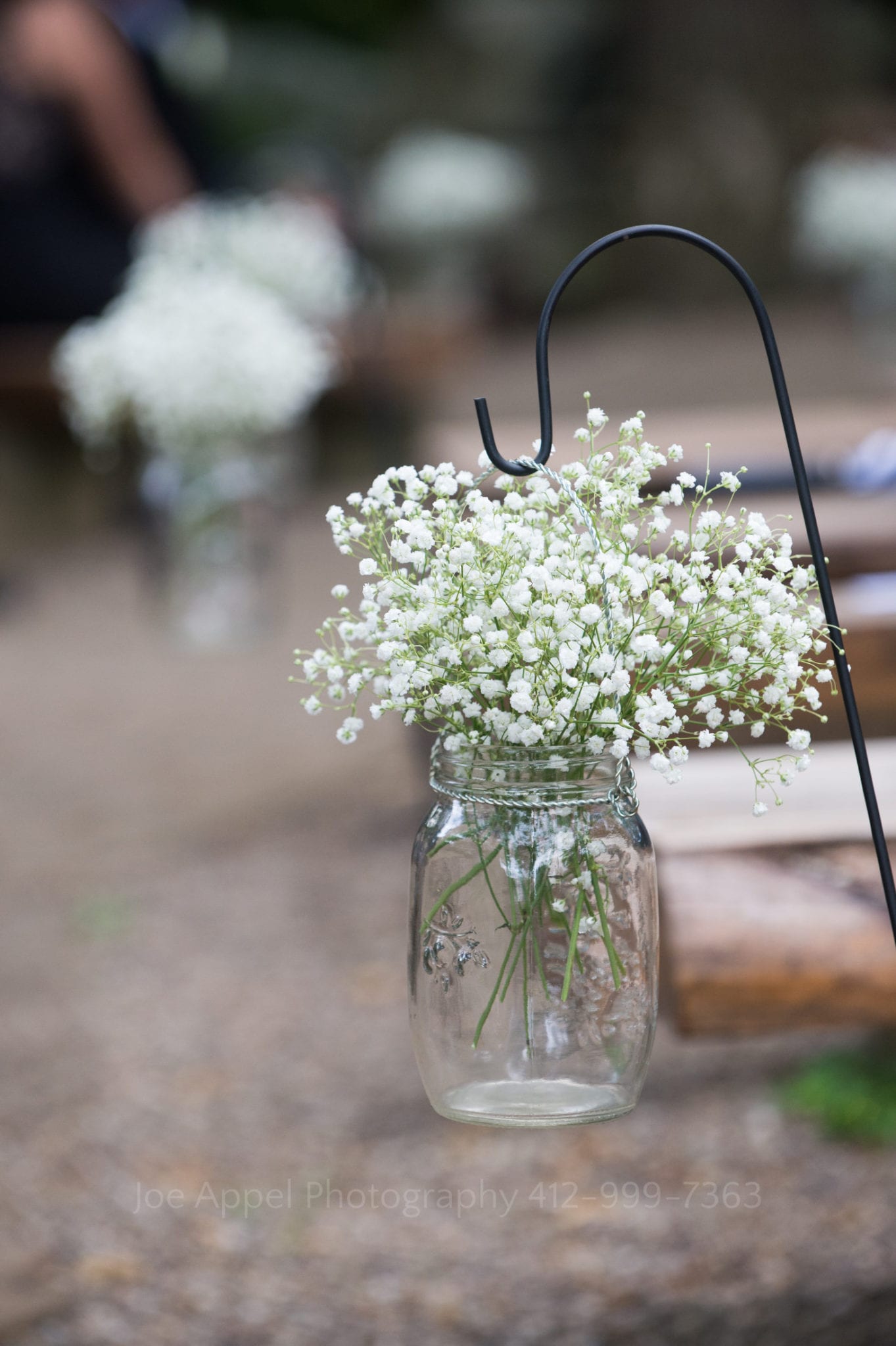 a mason jar of white flowers hangs from a hook Seven Springs Weddings