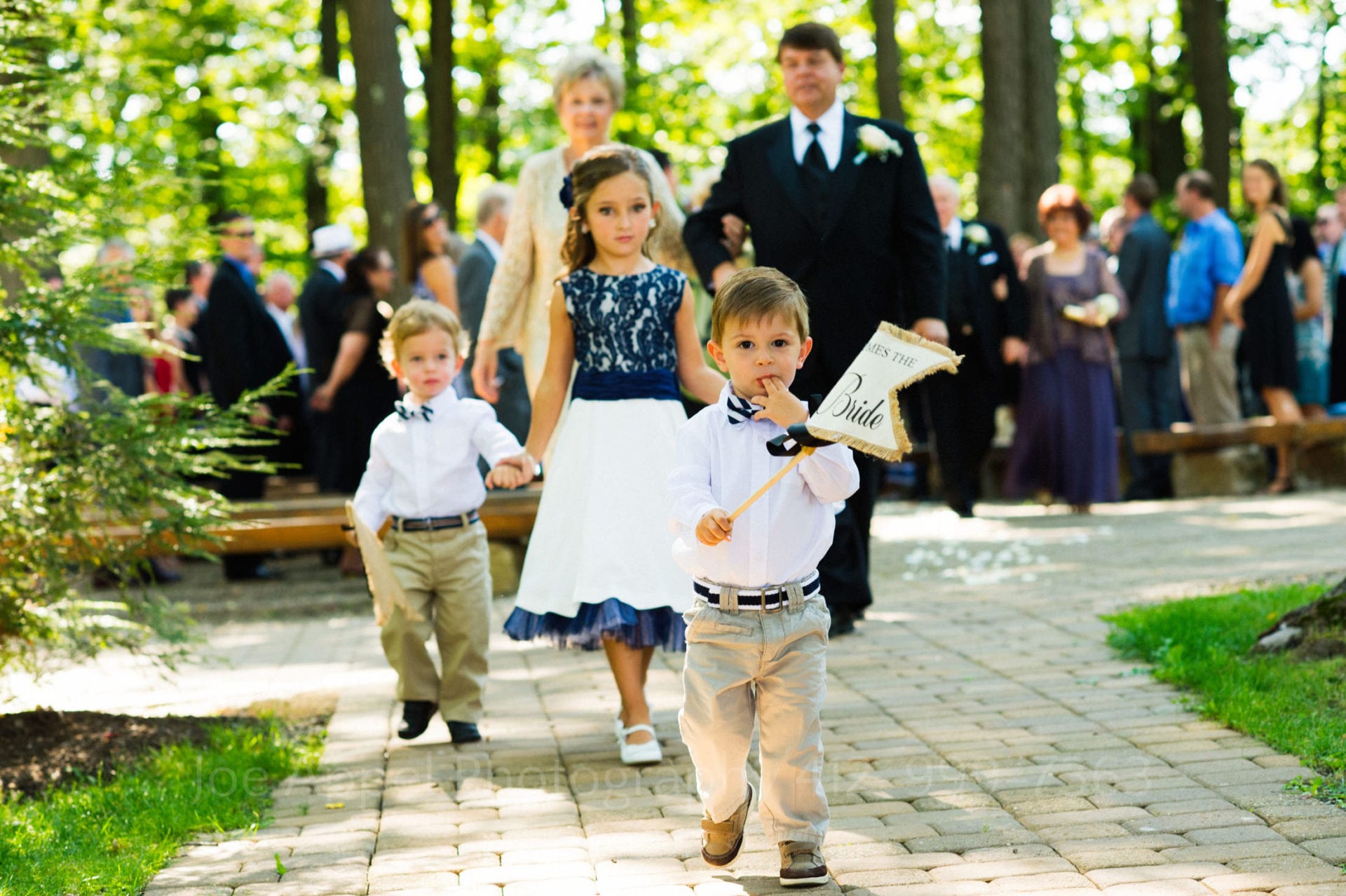 two little boys and a little girl in a blue and white dress walk down the aisle Seven Springs Weddings
