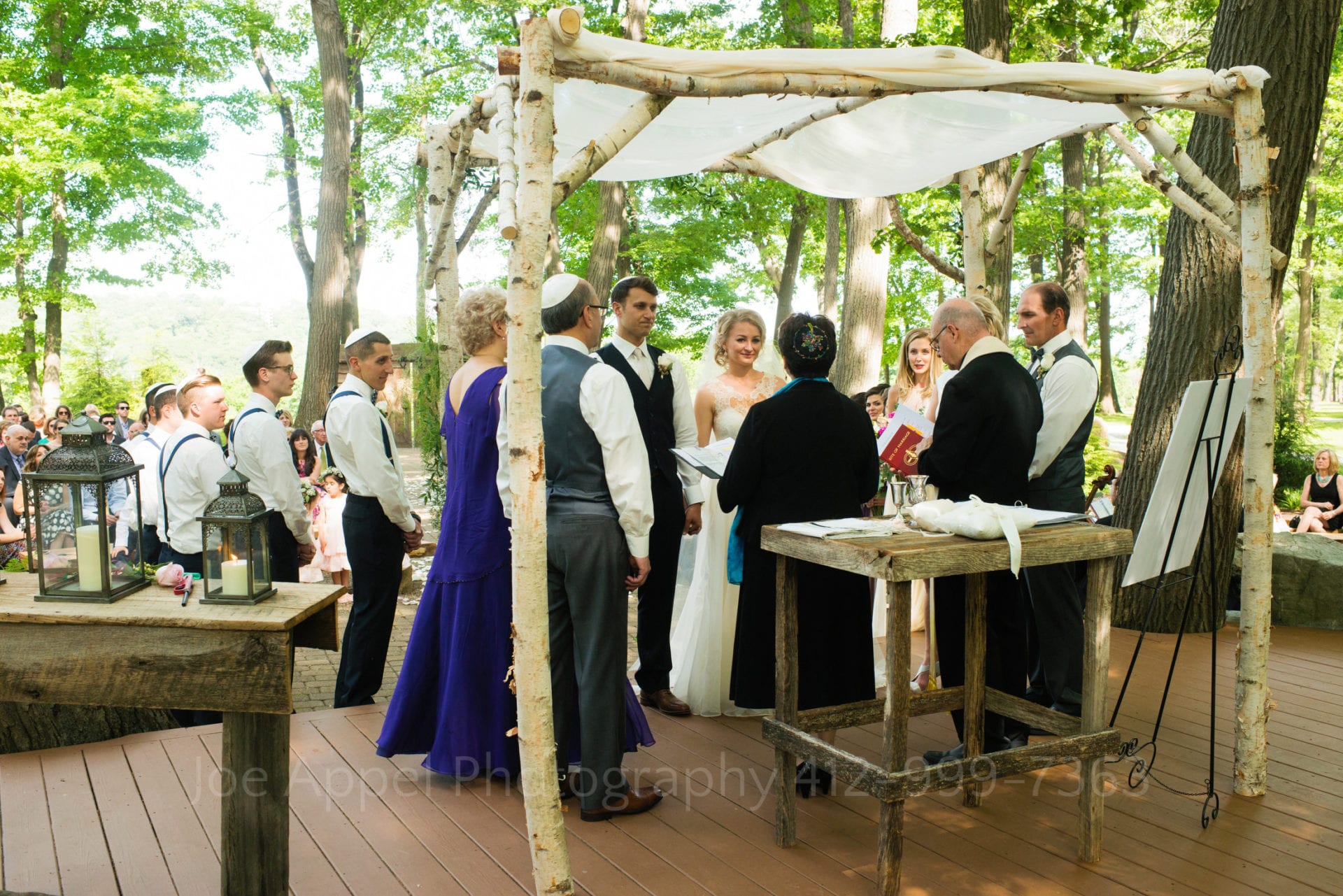 a bride and groom say their vows under a wooden chuppah Seven Springs Weddings