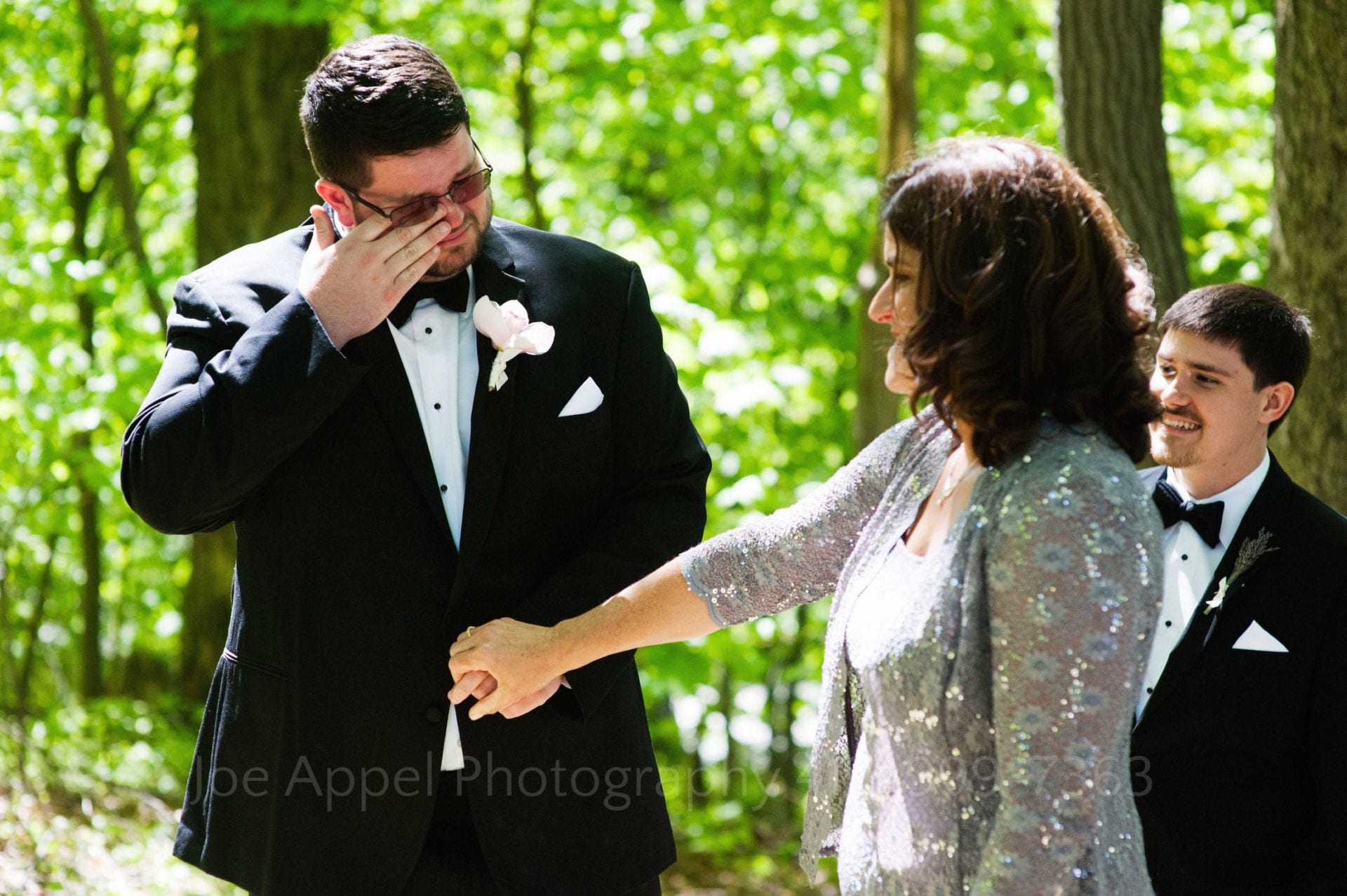 a woman holds a grooms hand as he cries Seven Springs Weddings