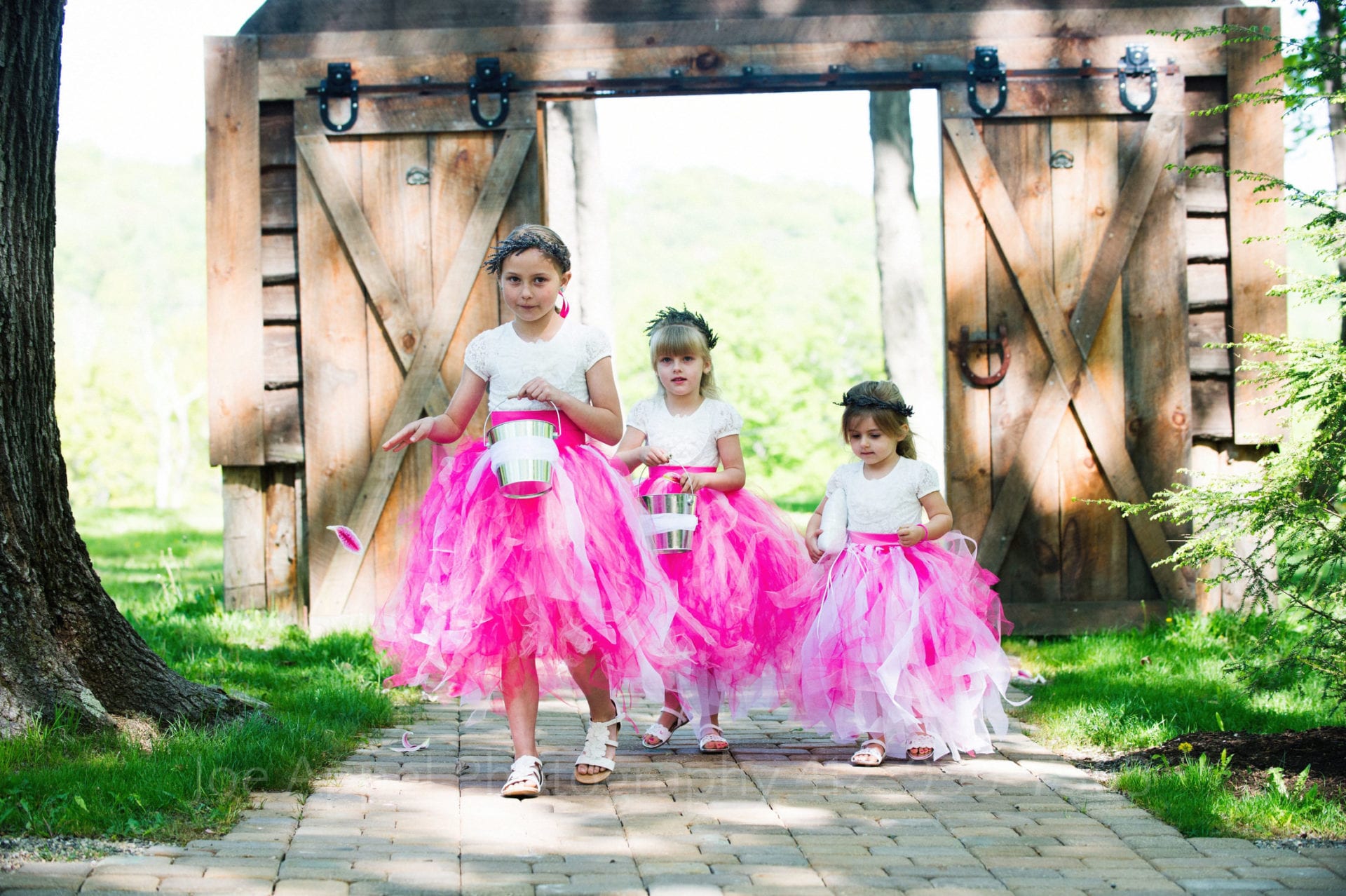 flower girls in pink dresses and green crowns walk down the aisle Seven Springs Weddings