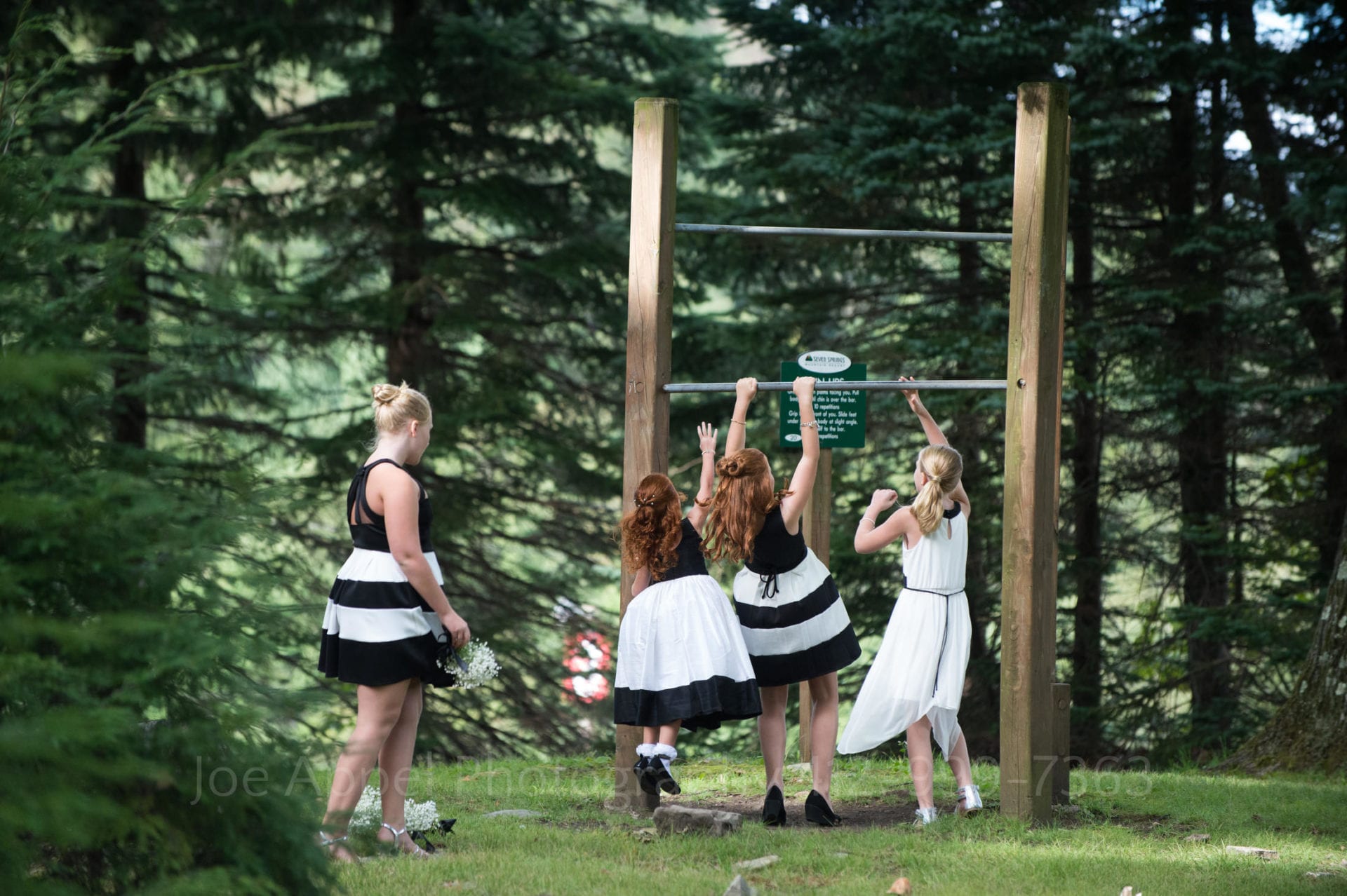 young girls in black and white dresses play with a pull up bar Seven Springs Weddings