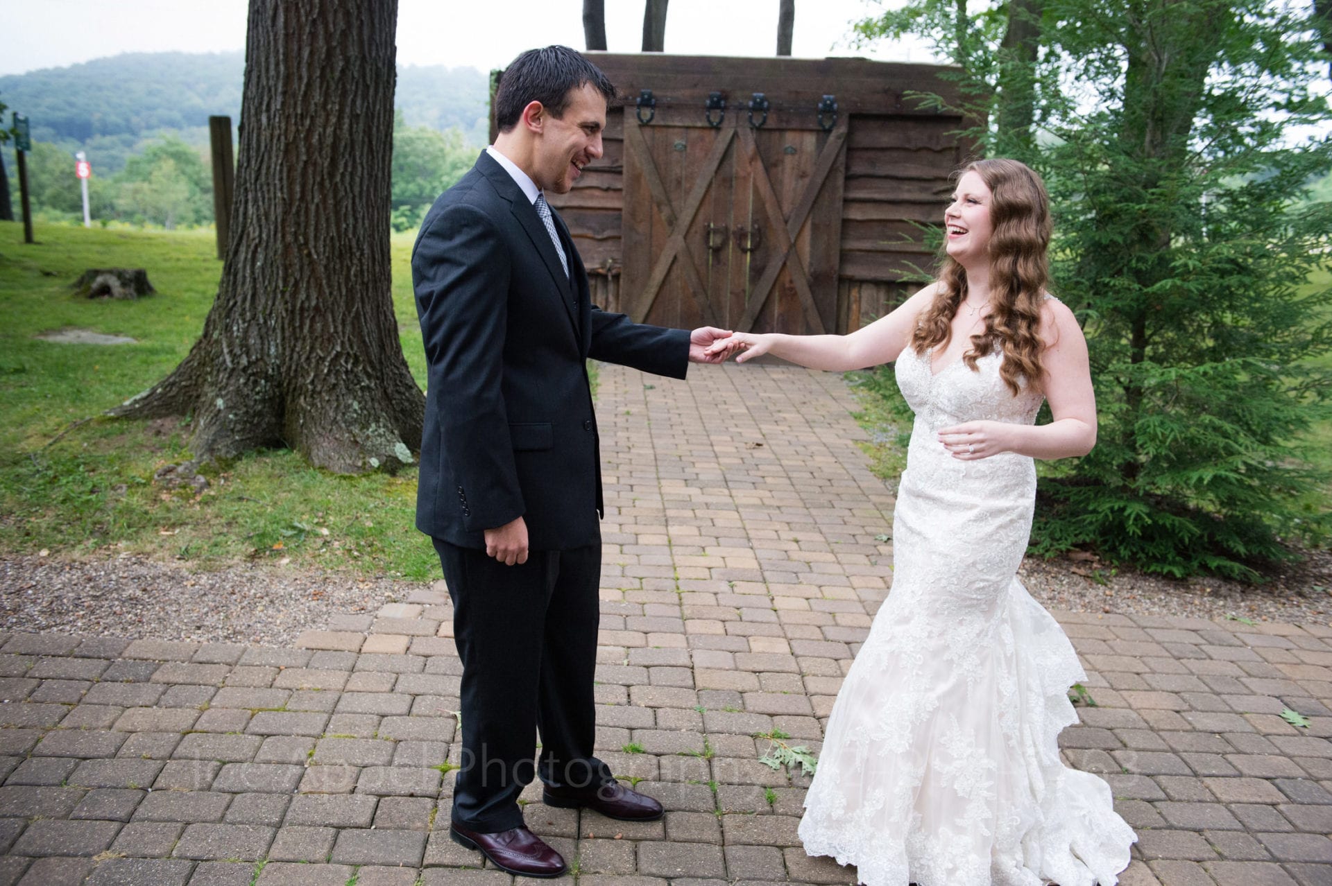 a bride and groom smile and hold hands on a forest path Seven Springs Weddings