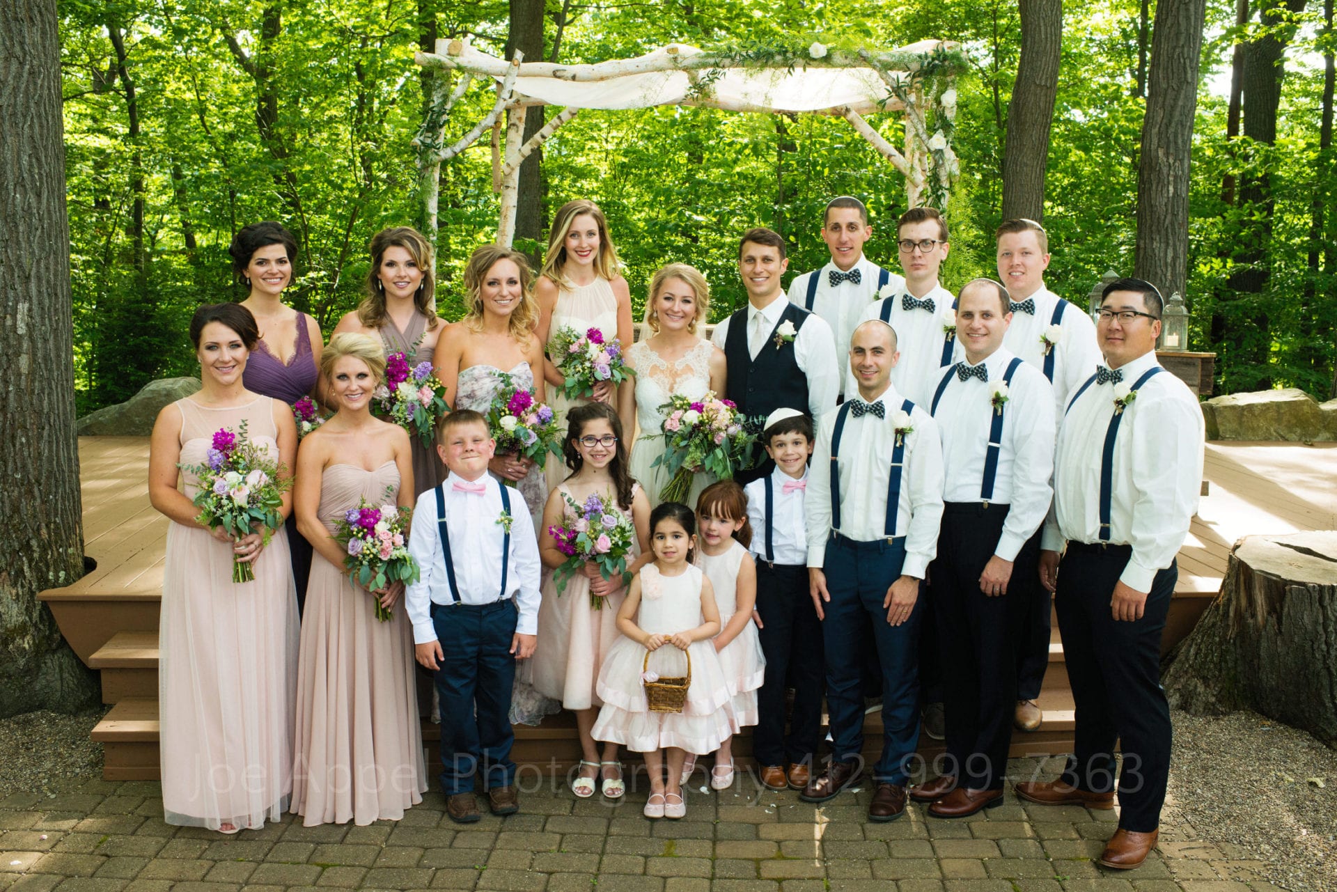 the entire wedding party stands in front of a chuppah Seven Springs Weddings