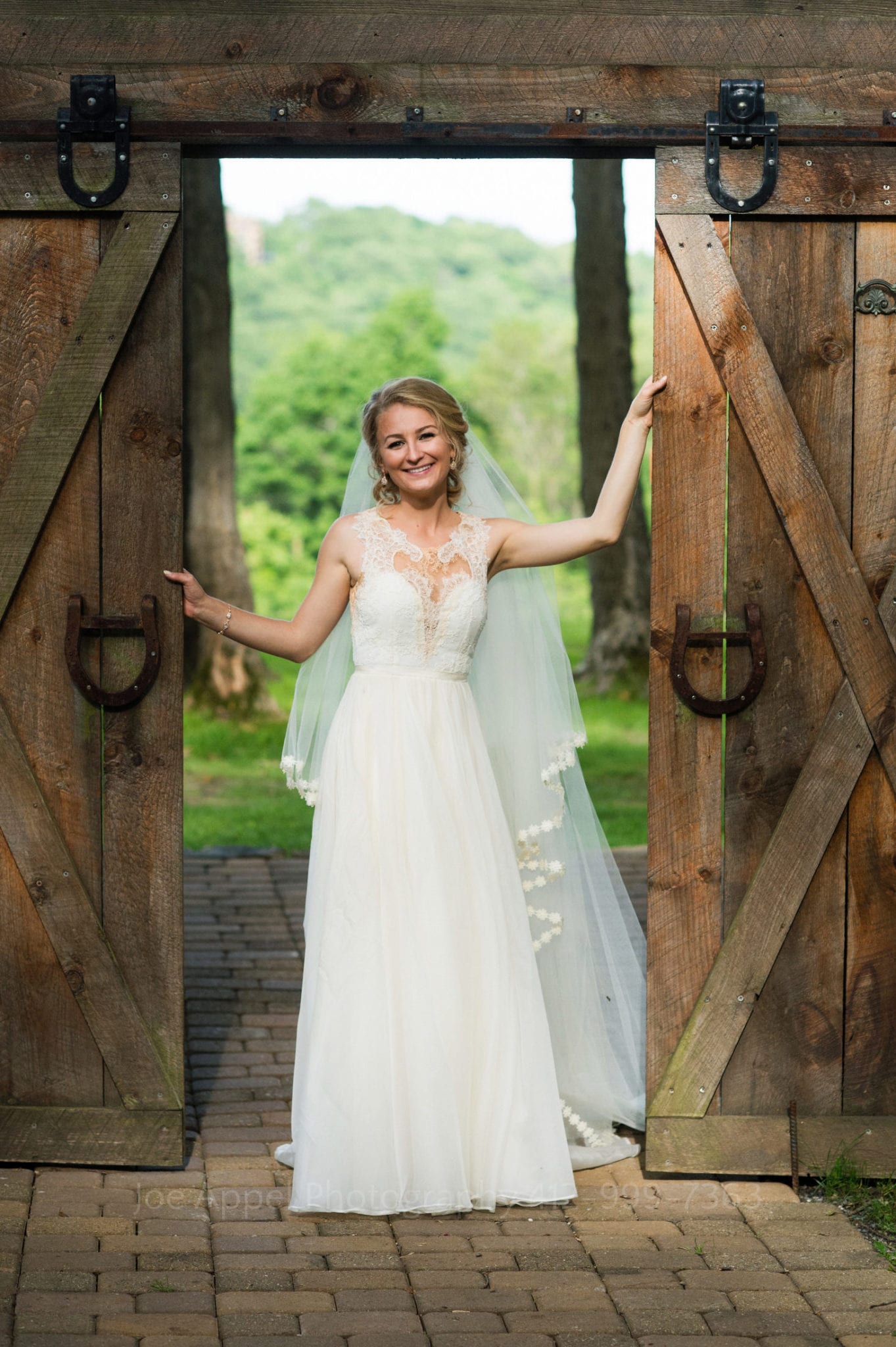 a bride smiles and poses by wooden stable doors Seven Springs Weddings
