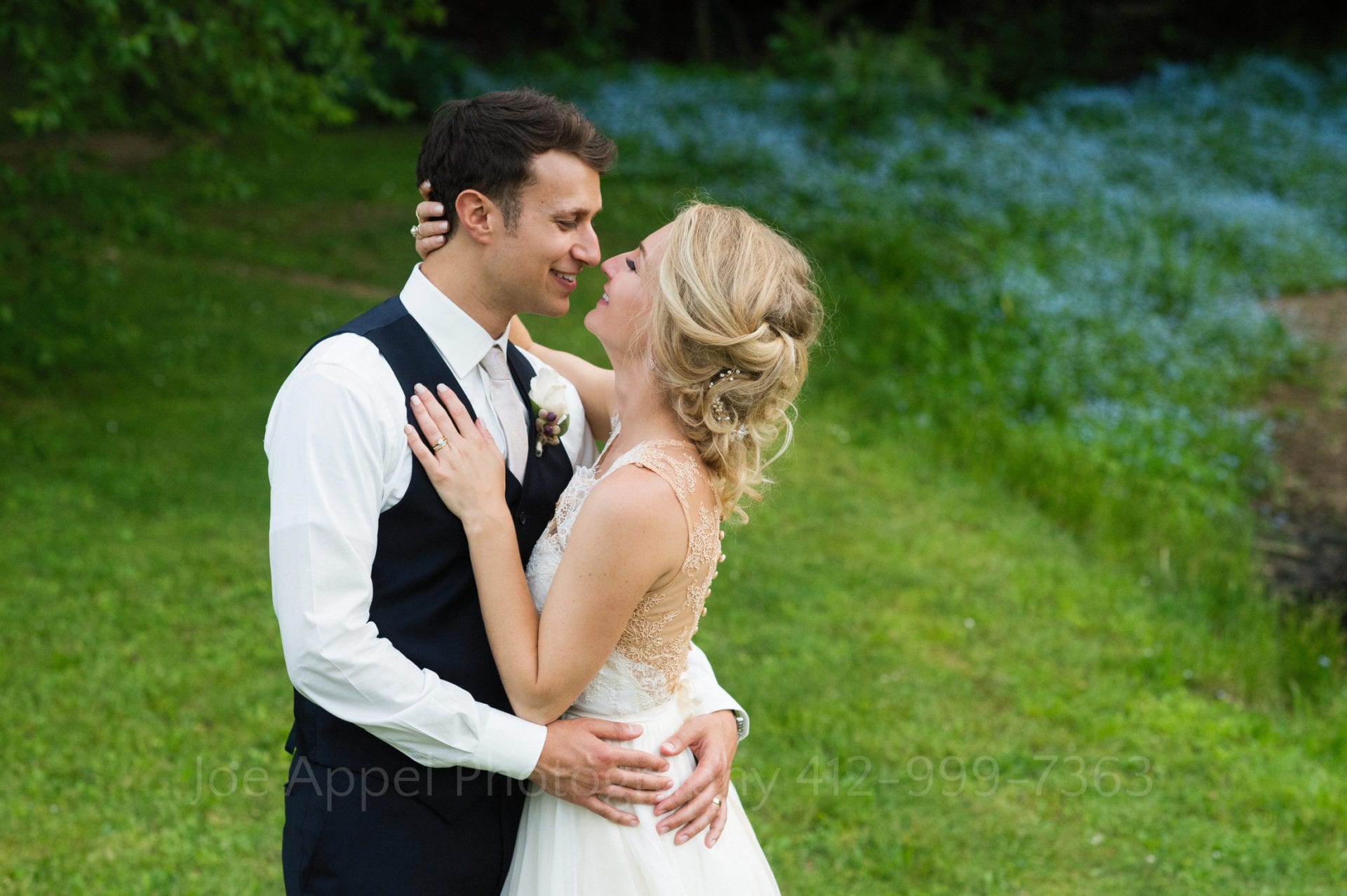 a bride and groom smile at each other and embrace in a grassy field Seven Springs Weddings