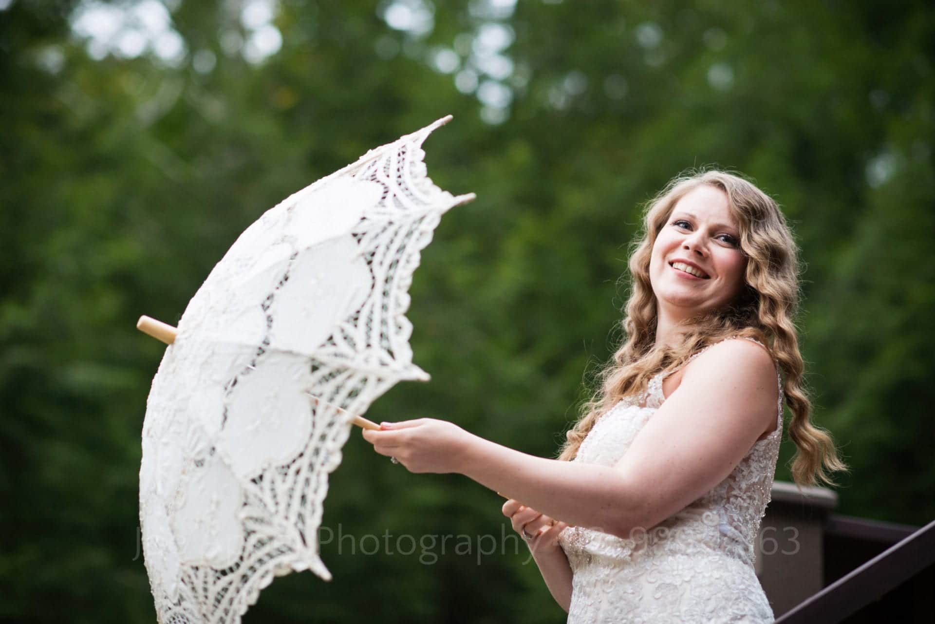 a bride smiles and opens a white parasol Seven Springs Weddings