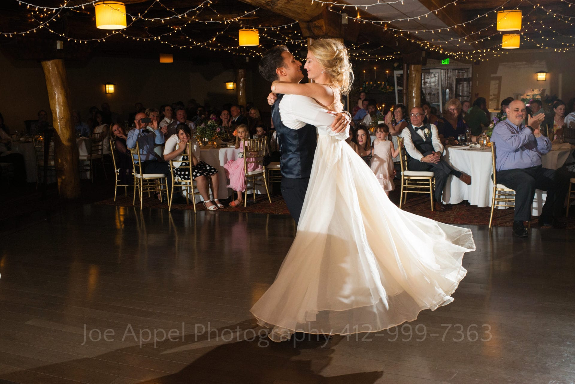 a groom picks his bride up on a dance floor with yellow lights Seven Springs Weddings