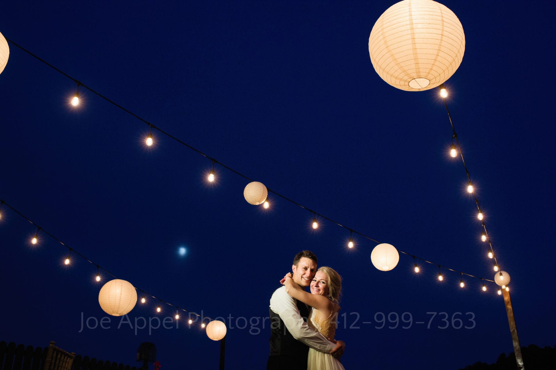 a bride and groom smile under lights and lanterns Seven Springs Weddings