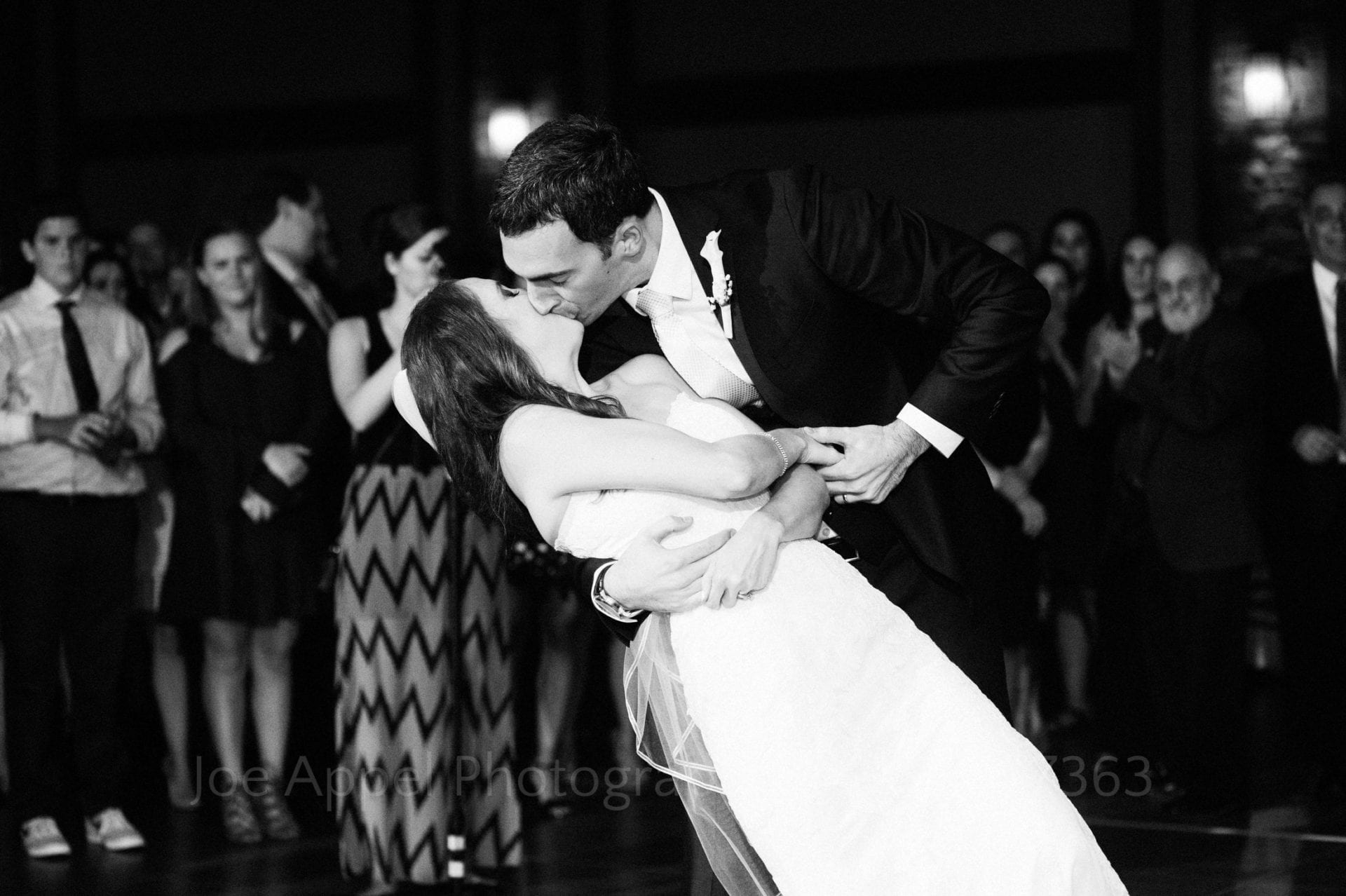 A groom dips his bride as they kiss at the end of their first dance.