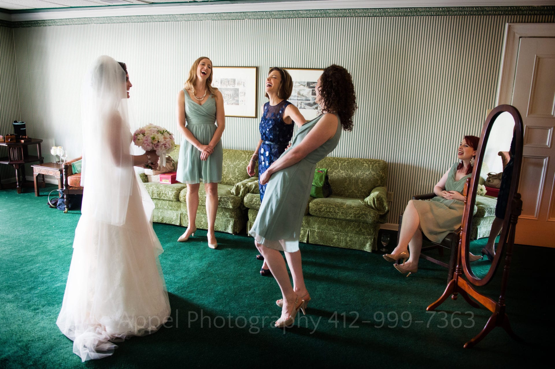 a bride laughs with her bridesmaids in a green room