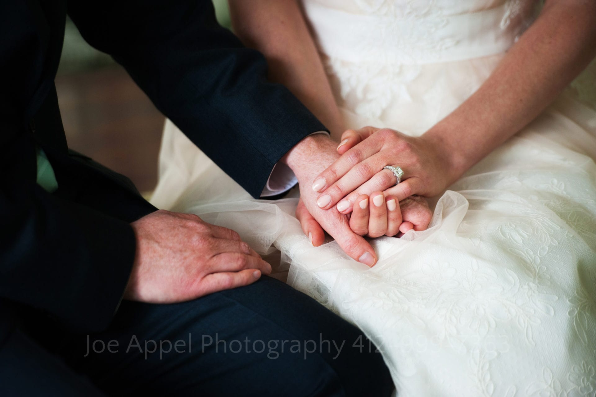 a bride with a large diamond wedding ring holds her grooms hand
