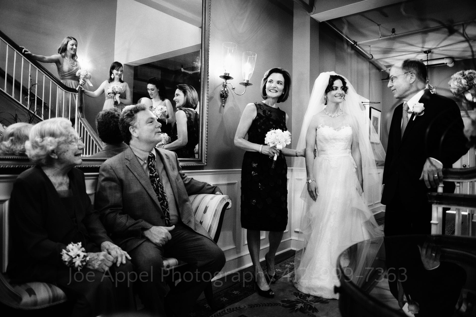 bridesmaids and family smile at the bride in her wedding dress