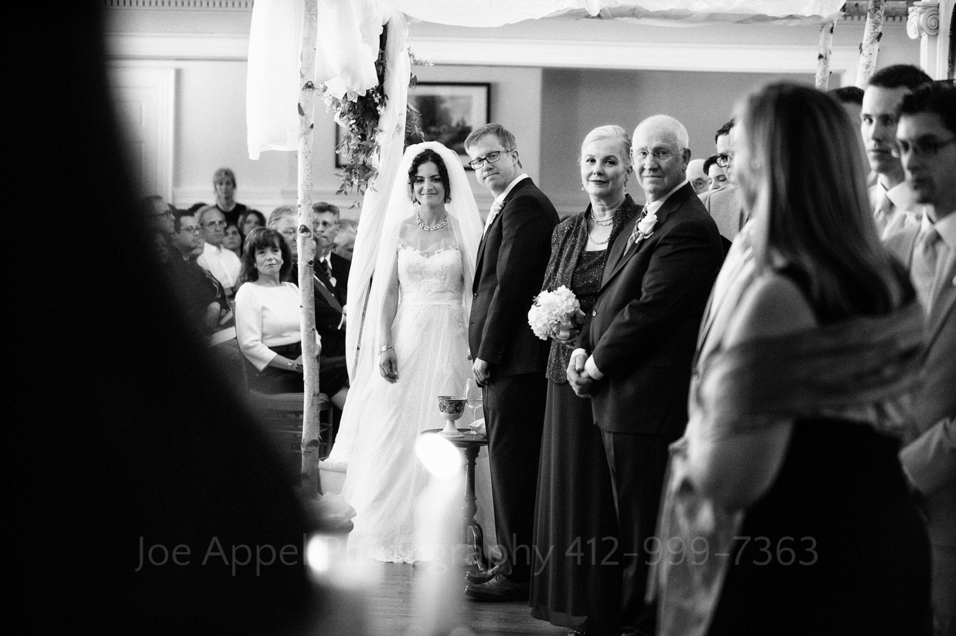 a bride and groom stand under their chuppah with their family