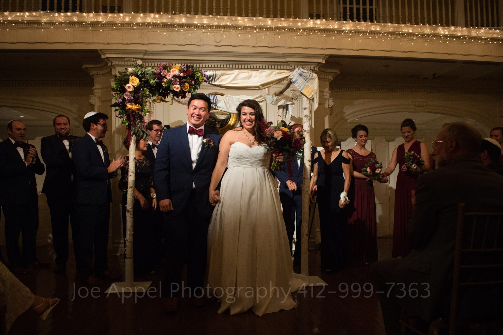a bride and groom stand under their chuppah in a room illuminated with fairy lights during their Pittsburgh Golf Club Weddings