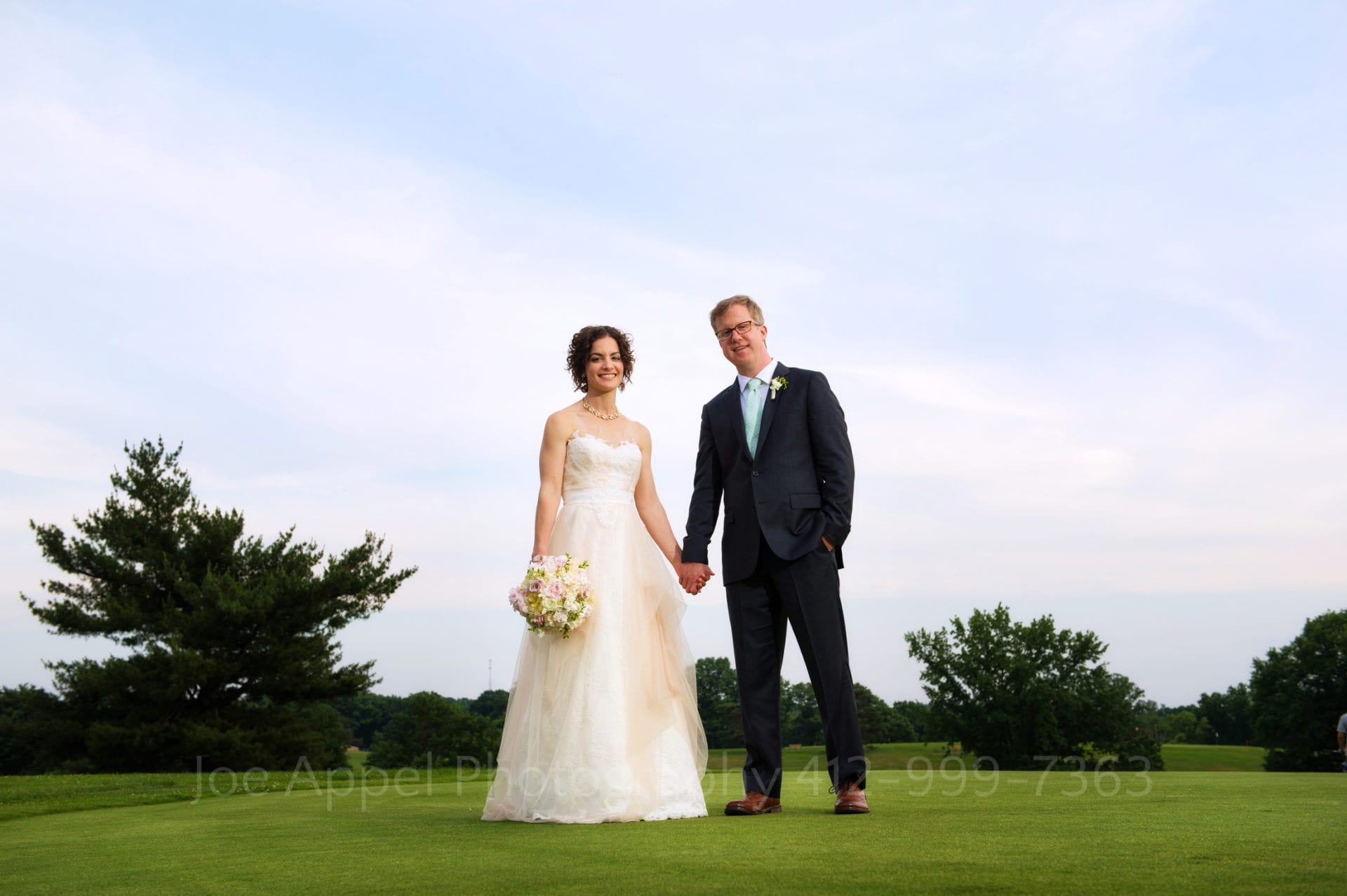 a bride and groom hold hands on a golf course